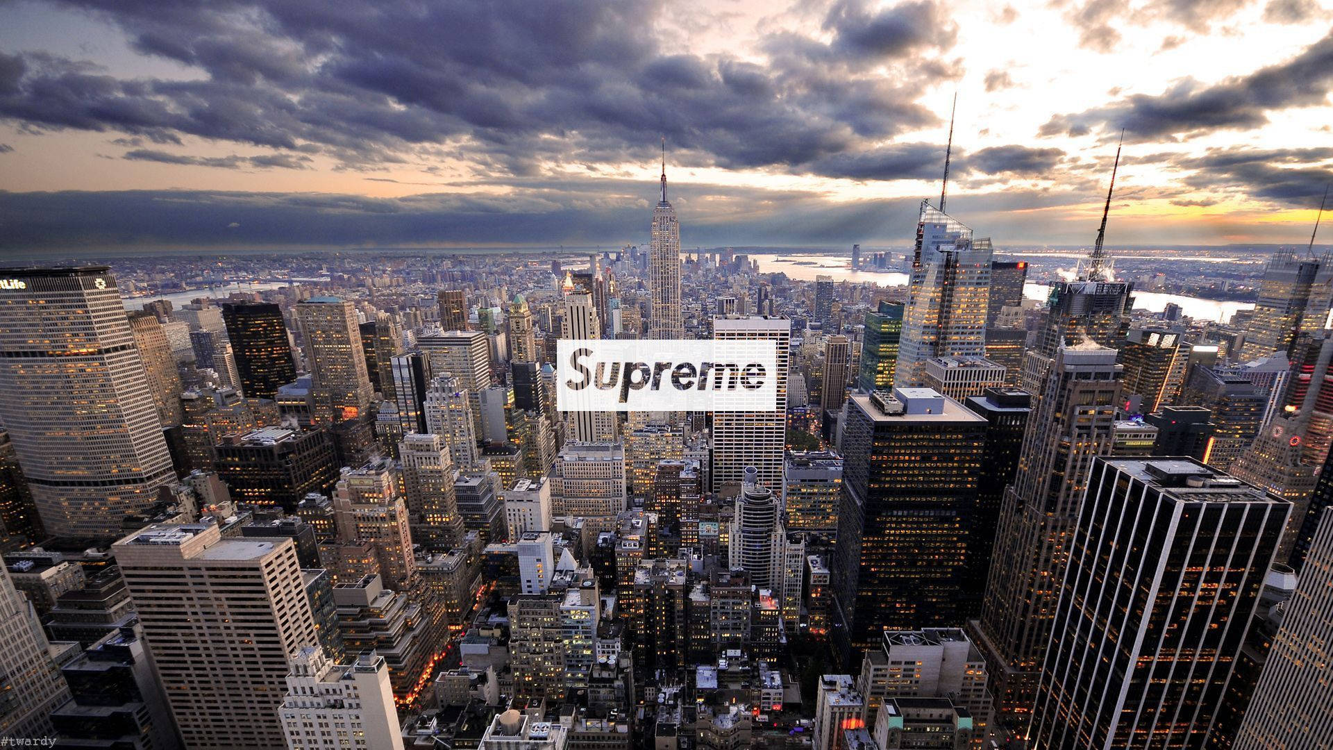 Cool Supreme 桌布 壁紙 — 紐約市天際線在黃昏時的戲劇性鳥瞰圖，雲層和燈火通明的摩天大樓上疊加著Supreme標誌。