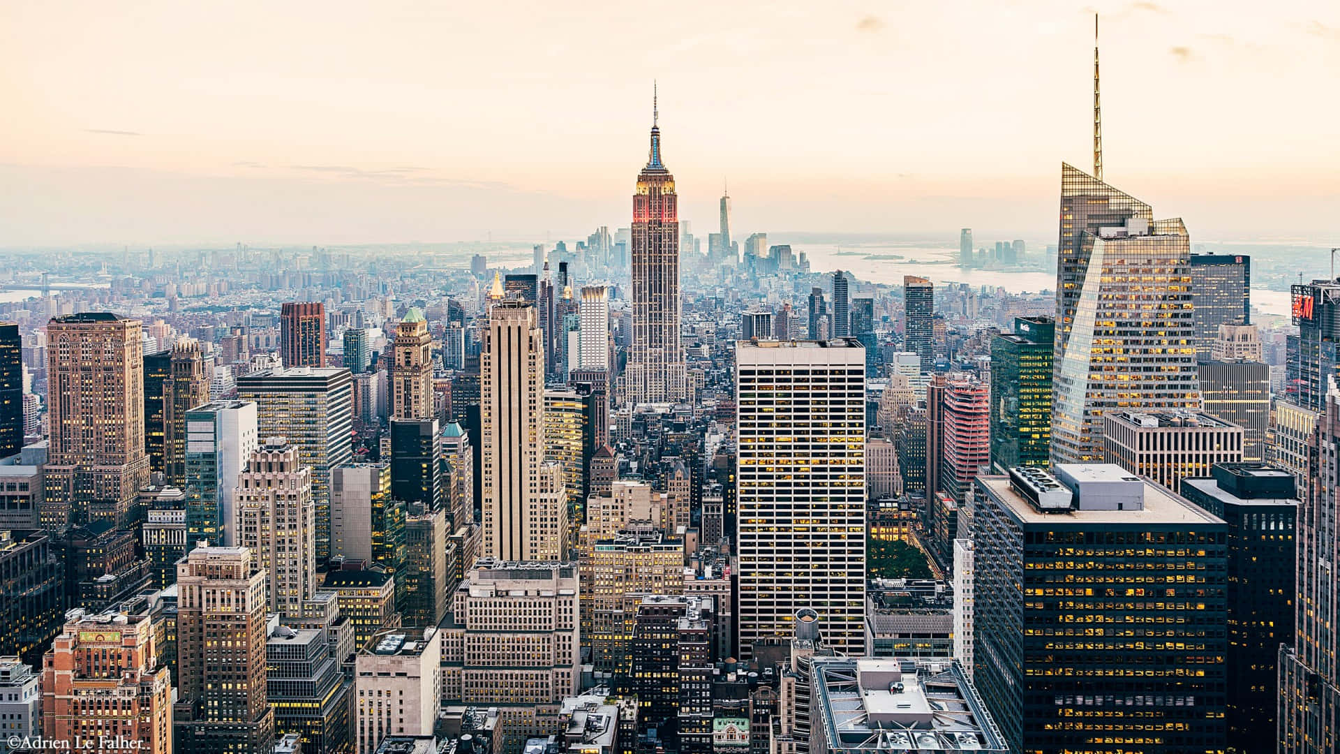 New York City Desktop 桌布 壁紙 — 紐約市天際線在黃昏時的鳥瞰圖，帝國大廈在柔和的橙色和粉紅色天空下亮起。