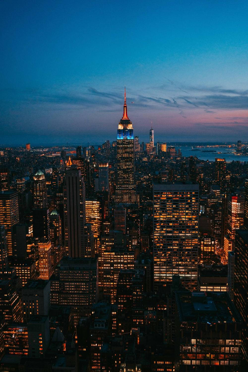 New York 桌布 壁紙 — 紐約市天際線在黃昏時的鳥瞰圖，帝國大廈在漸變的藍色和紫色天空中亮起。