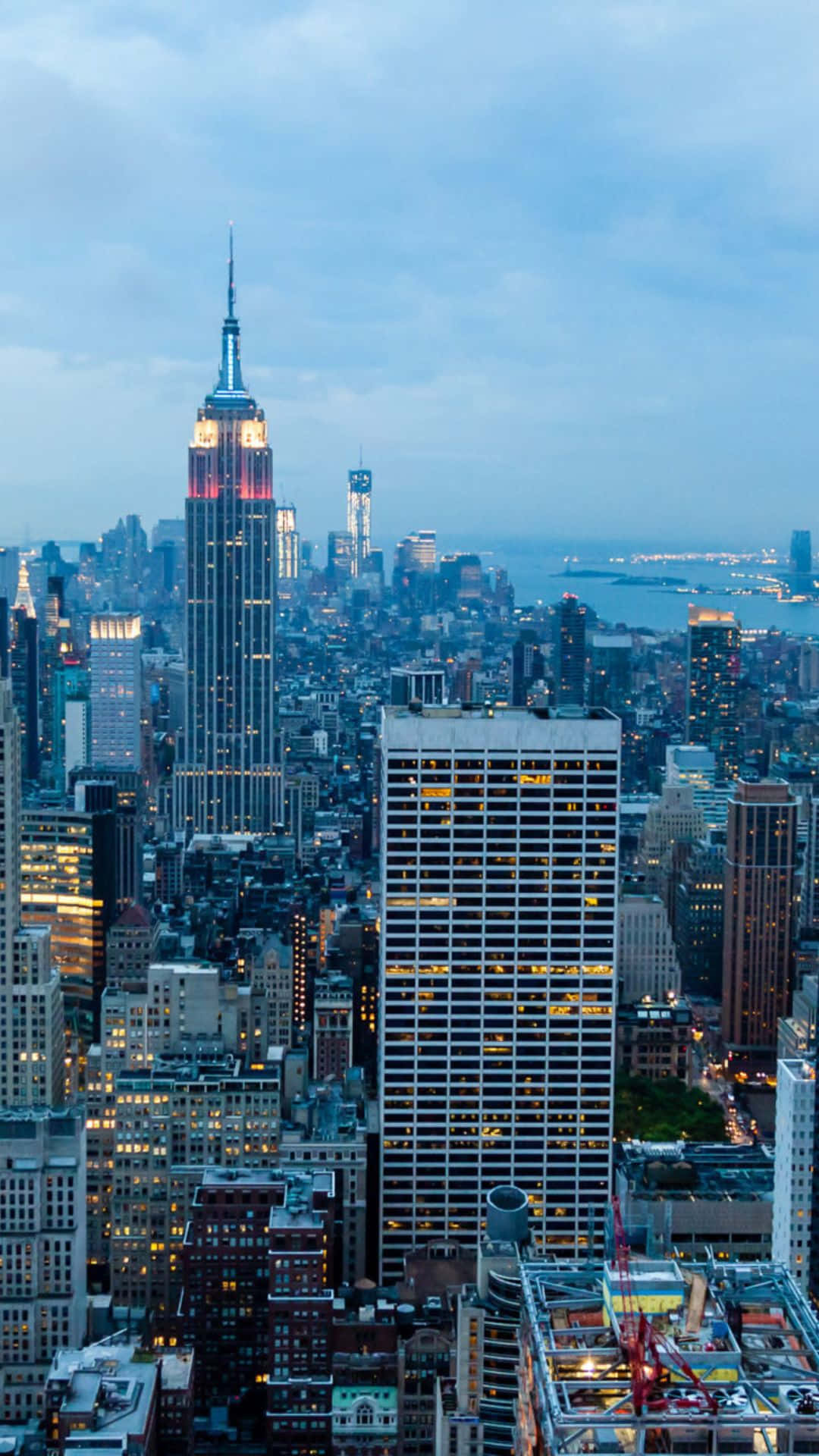 Android Ny City 桌布 壁紙 — 紐約市天際線在黃昏時的鳥瞰圖，帝國大廈在多雲的天空下亮起燈光。