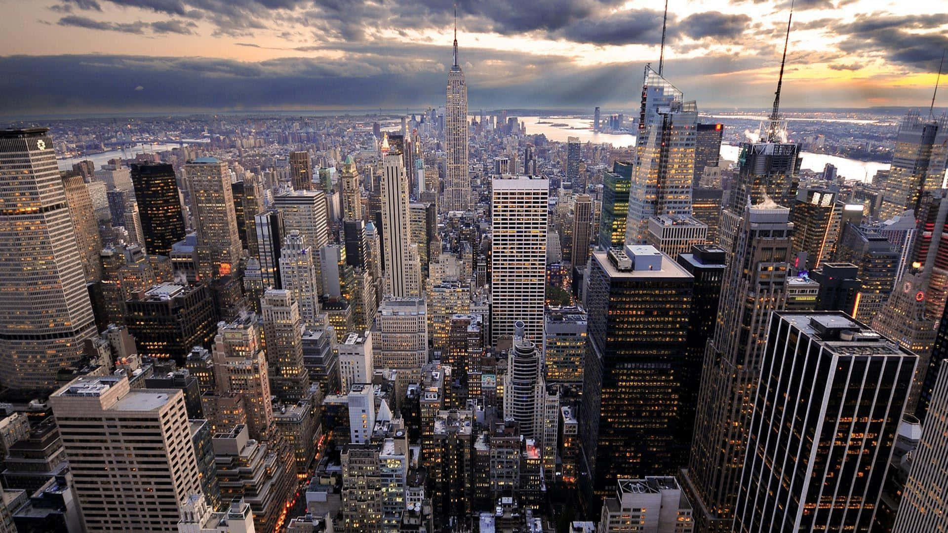Nyc 桌布 壁紙 — 紐約市天際線在黃昏時的鳥瞰圖，摩天大樓燈火通明，上方有戲劇性的雲層。