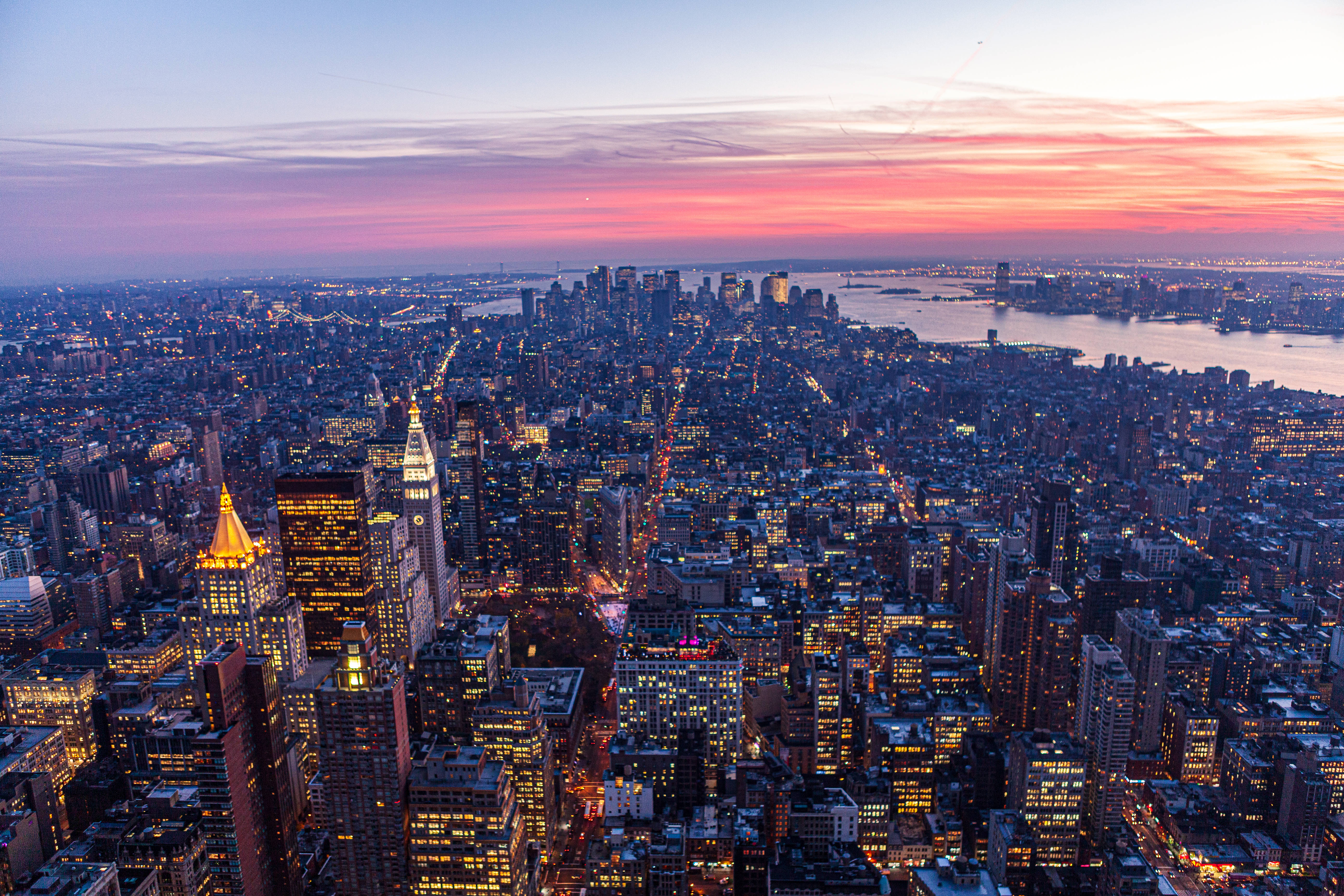 empire state 桌布 壁紙 — 紐約市天際線在黃昏時的鳥瞰圖，粉橙色天空和發光的摩天大樓。