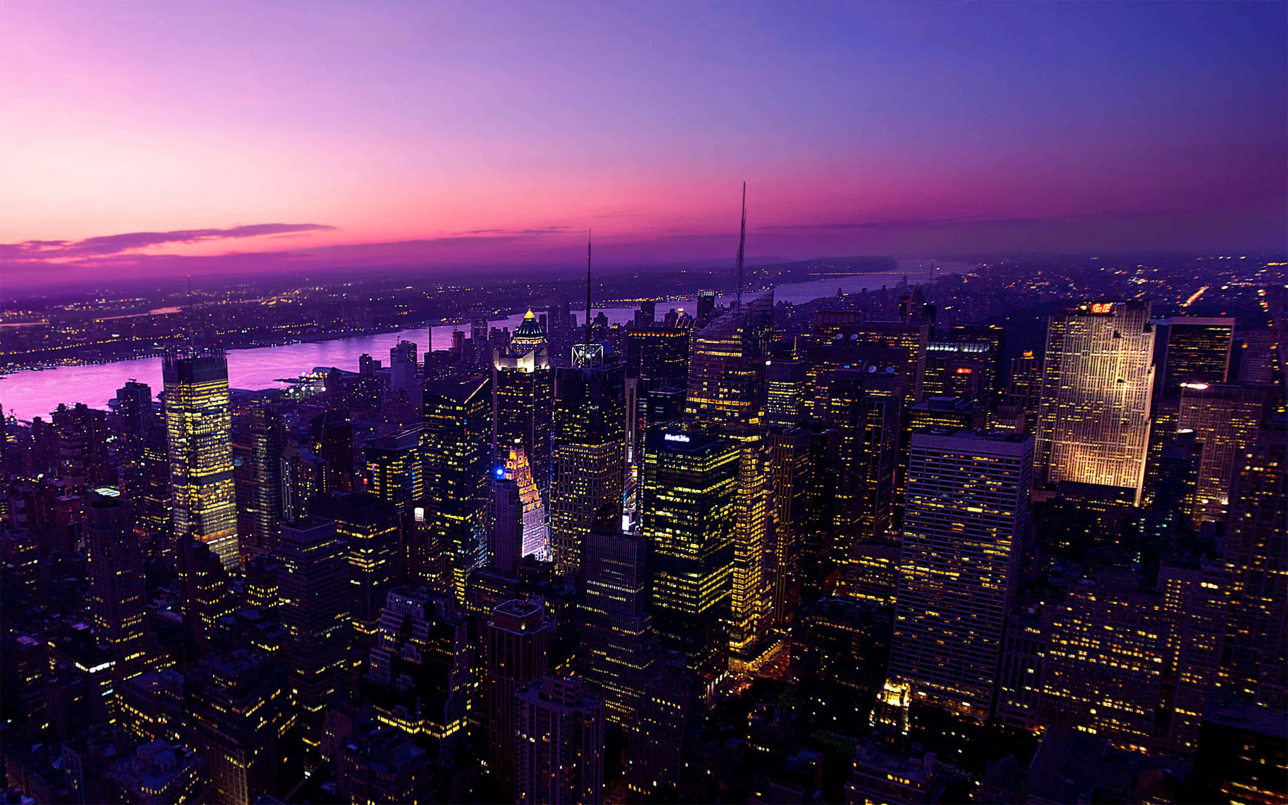 桌布 壁紙 — 紐約市天際線在黃昏時的鳥瞰圖，紫粉色的天空和發光的摩天大樓倒映在水面上。