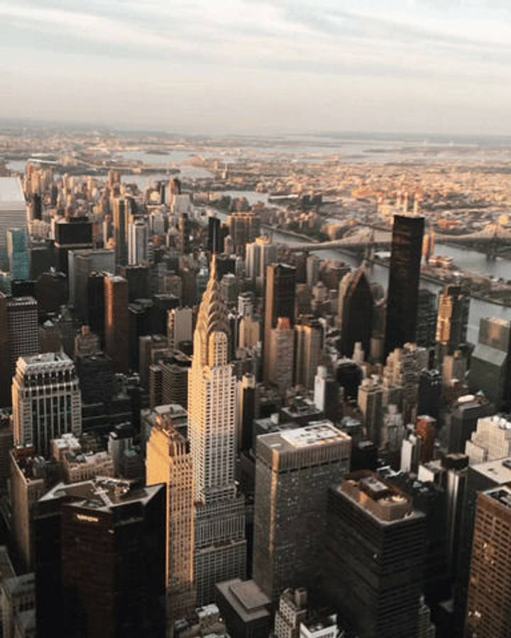 empire state 桌布 壁紙 — 紐約市天際線在黃金時刻的鳥瞰圖，摩天大樓和橋樑沐浴在溫暖的陽光中。