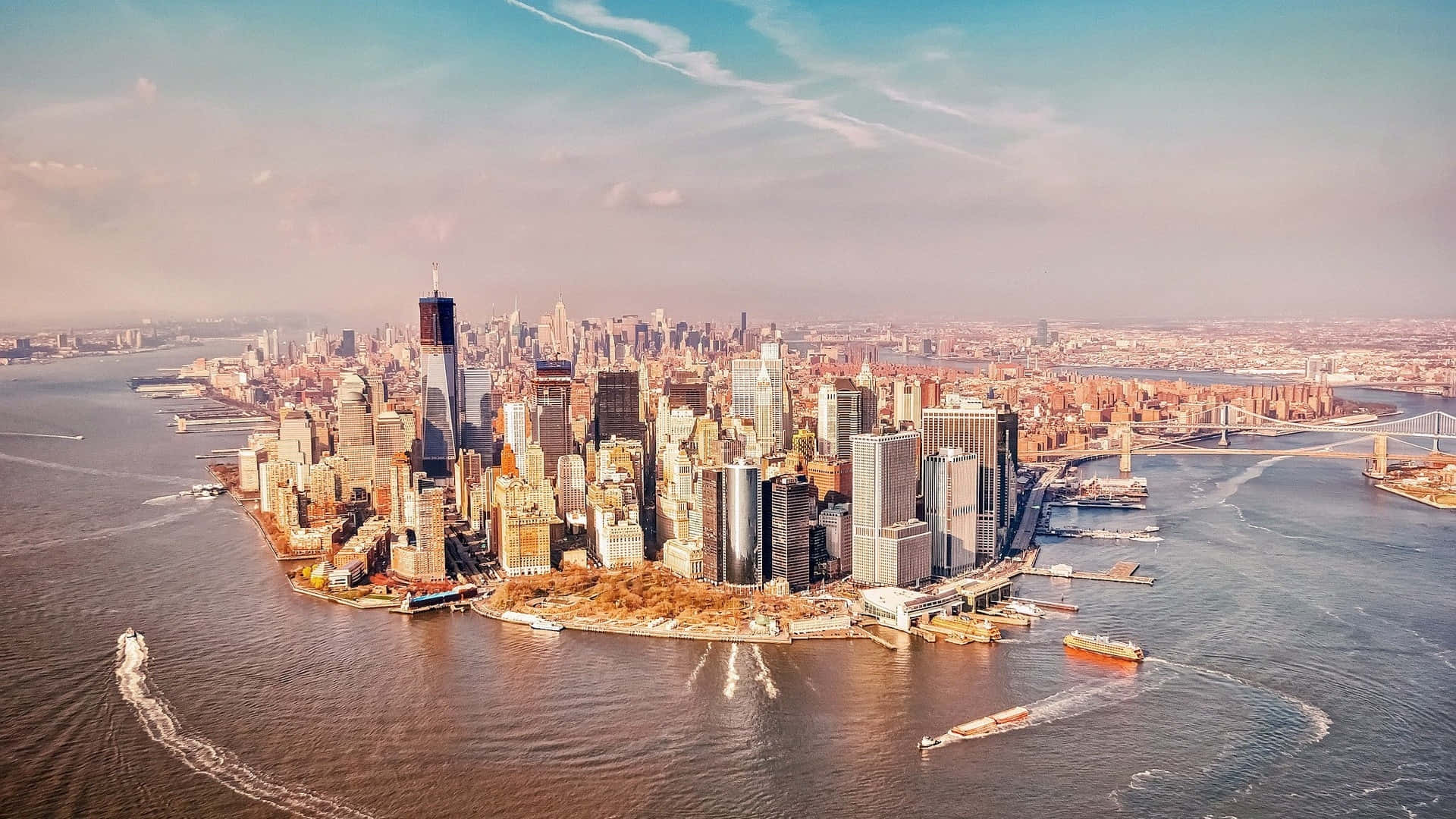 Nyc 桌布 壁紙 — 紐約市天際線在黃金時刻的鳥瞰圖，摩天大樓將溫暖的光線反射到周圍的水道上。