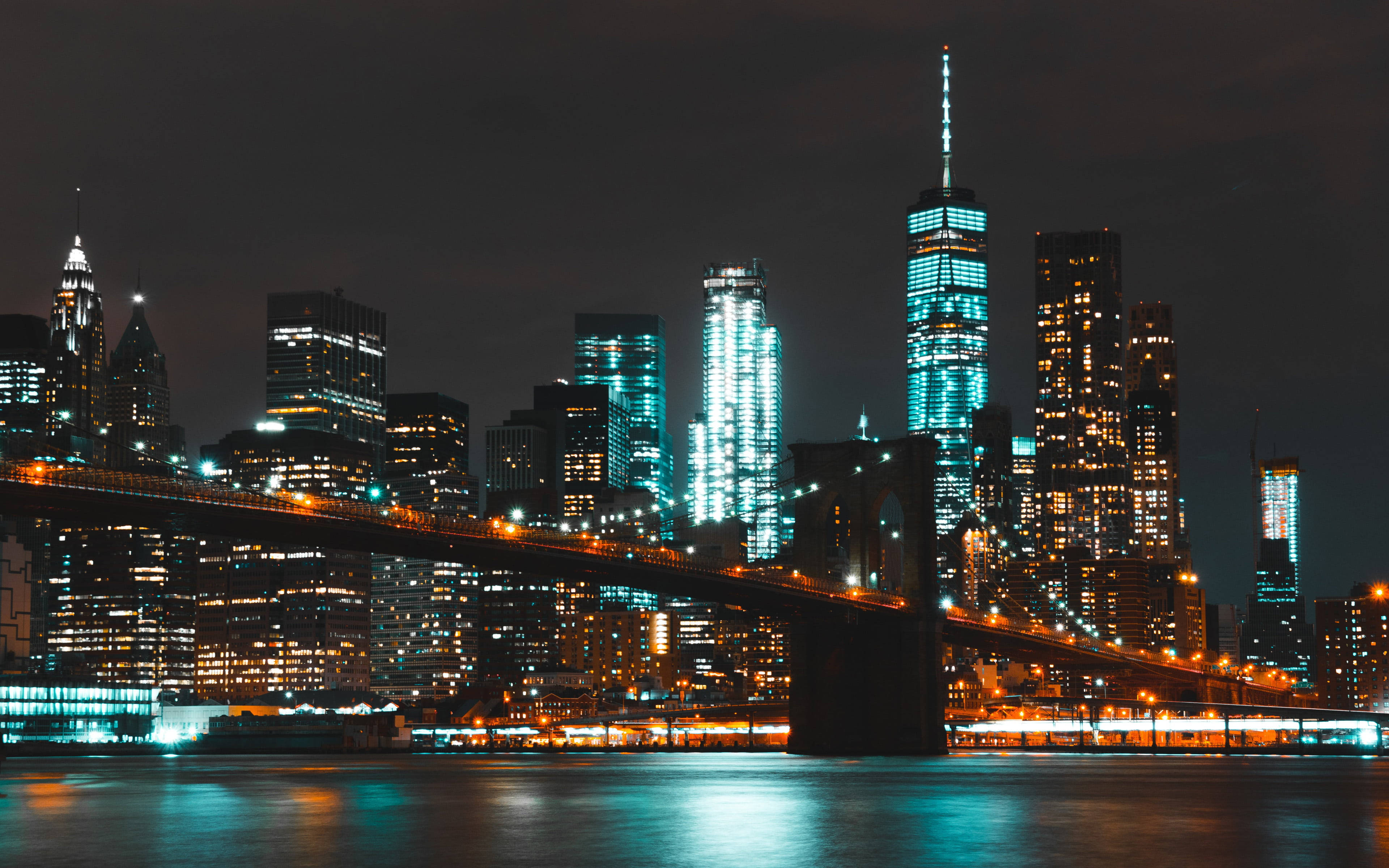 New York 桌布 壁紙 — 紐約市天際線的充滿活力的夜景，閃爍的摩天大樓和布魯克林大橋倒映在平靜的水面上。