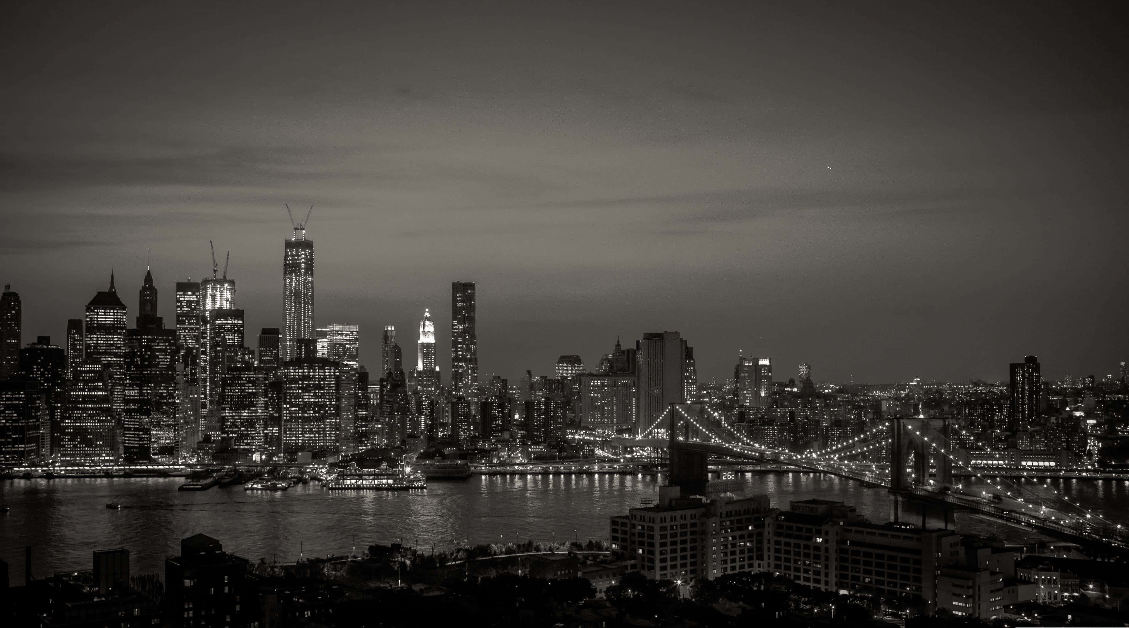 城市 桌布 壁紙 — 紐約市天際線的單色夜景全景，布魯克林大橋在城市燈光下閃耀。