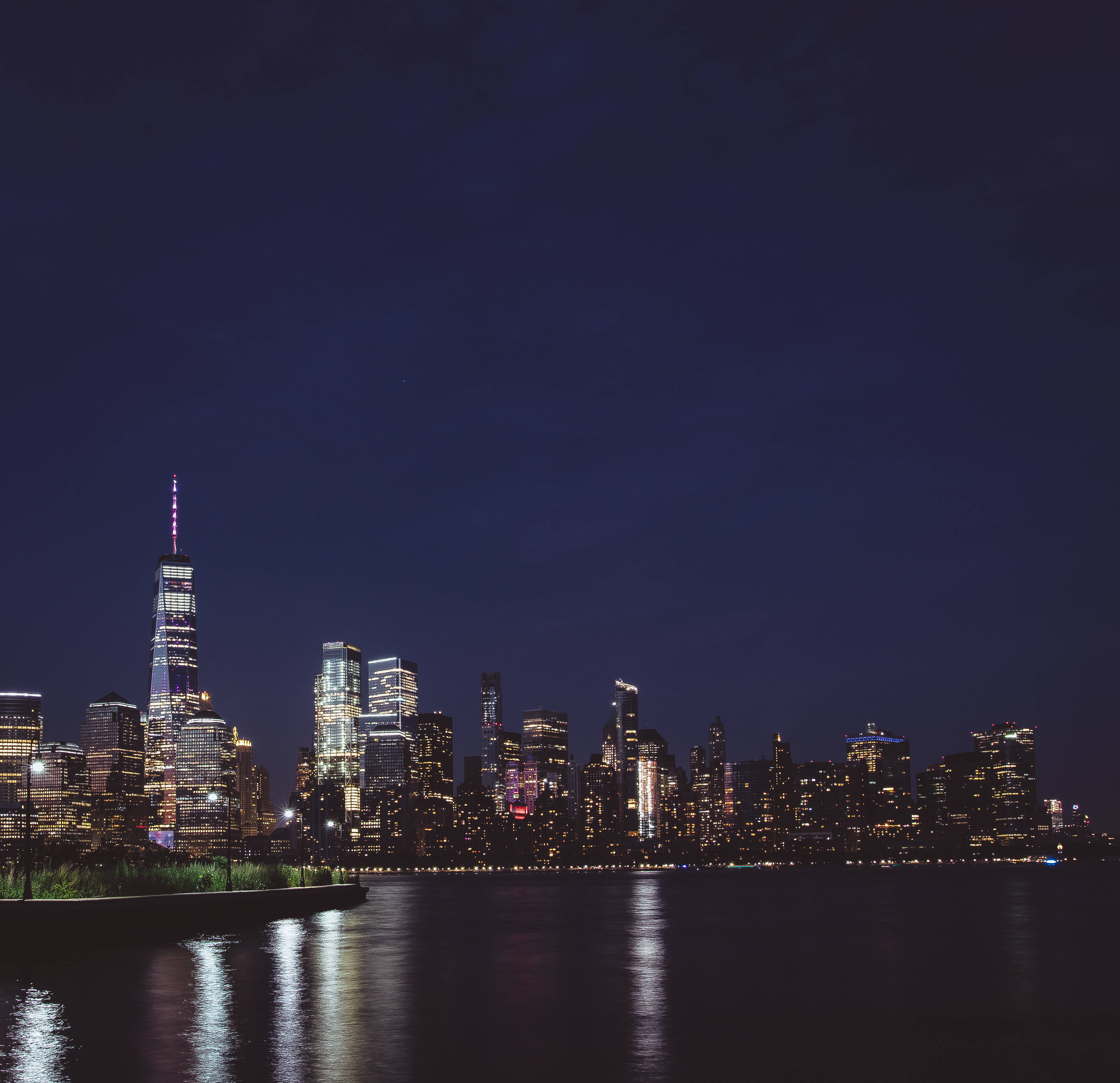 New 桌布 壁紙 — 紐約市天際線的壯麗夜景，燈火通明的摩天大樓倒映在平靜的水面上。