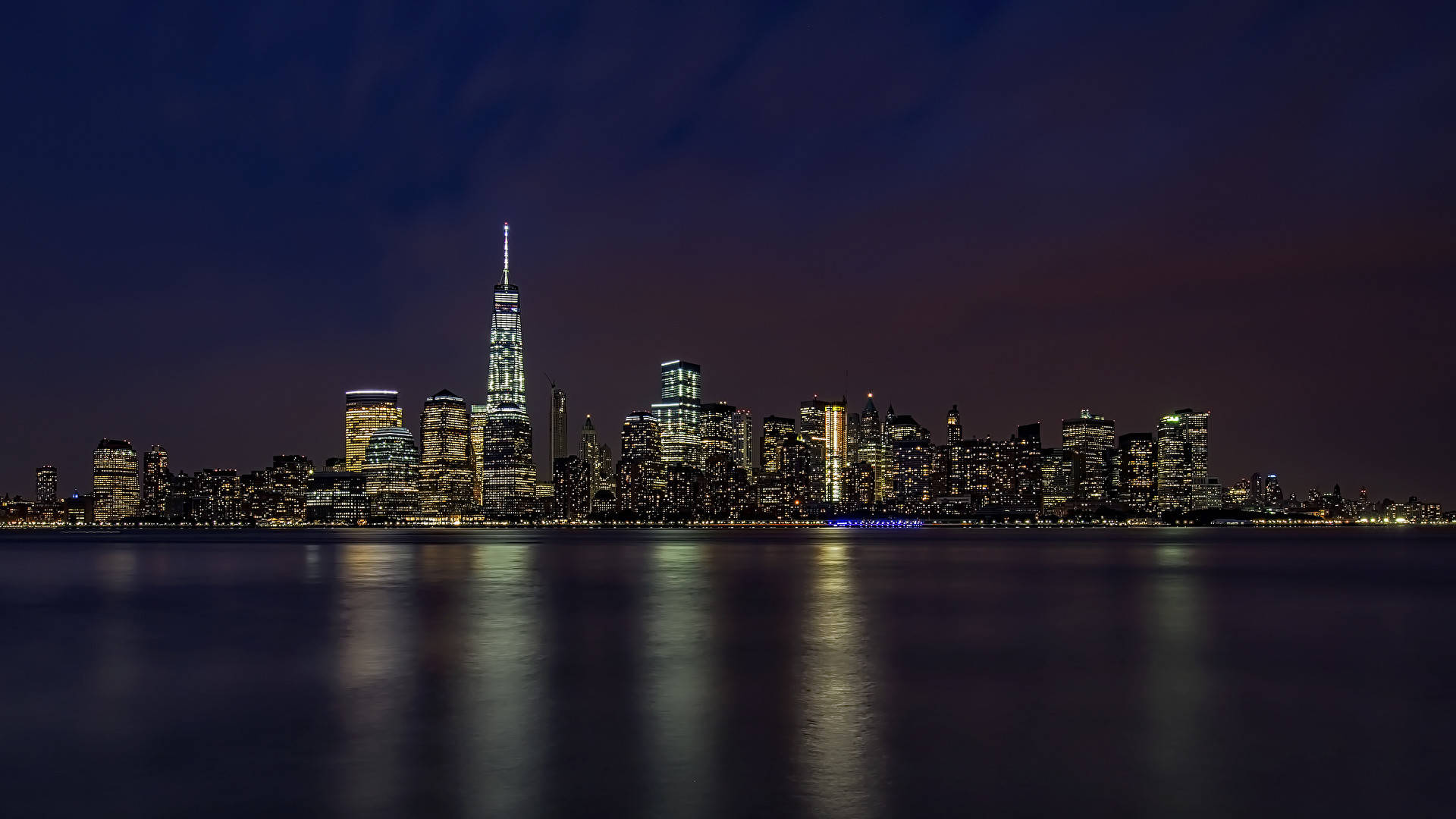 New 桌布 壁紙 — 紐約市天際線的壯麗夜景，燈火通明的摩天大樓倒映在平靜的水面上。