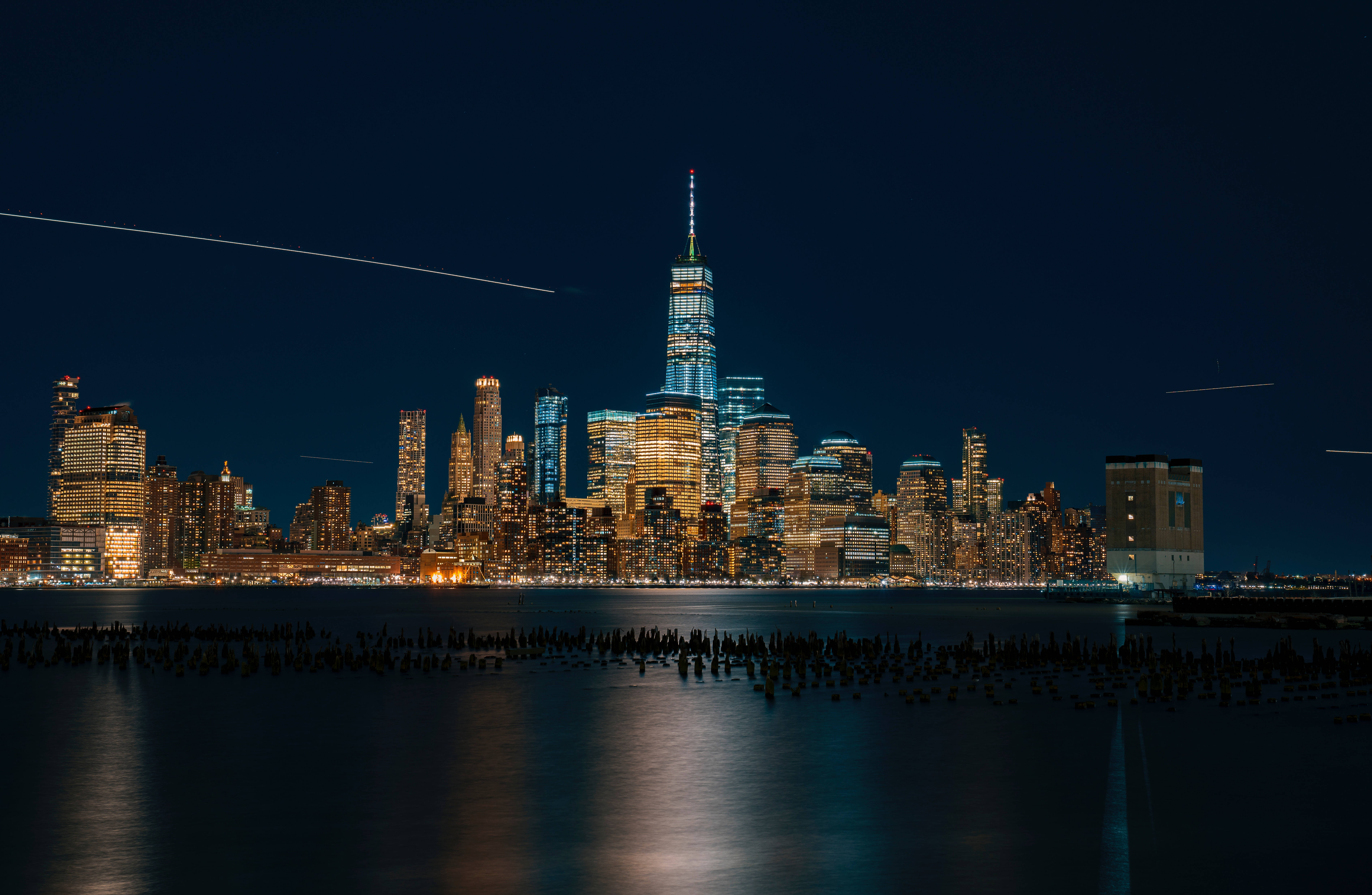 Skyscraper 桌布 壁紙 — 紐約市天際線的壯麗夜景，燈火通明的摩天大樓倒映在平靜的水面上。