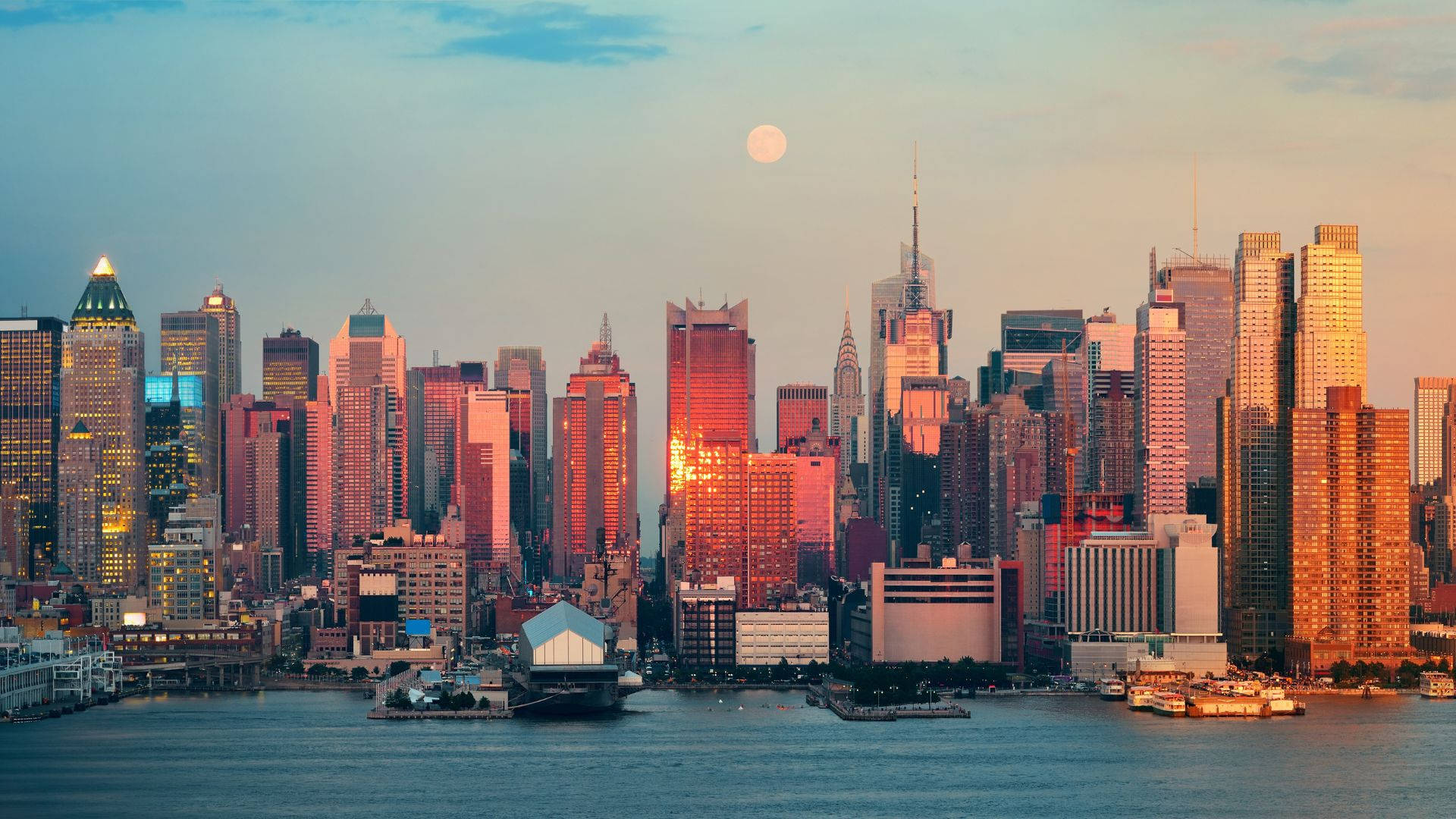 New York City Desktop 桌布 壁紙 — 紐約市天際線的壯麗日落，滿月升起在高聳的摩天大樓之上，倒映在水中。