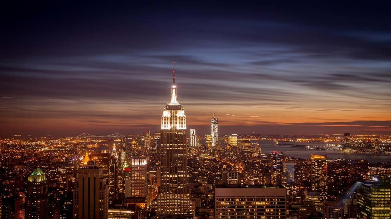 1366x768 Empire State Building 桌布 壁紙 — 紐約市天際線的壯麗暮色景觀，帝國大廈在漸變的天空中閃耀。