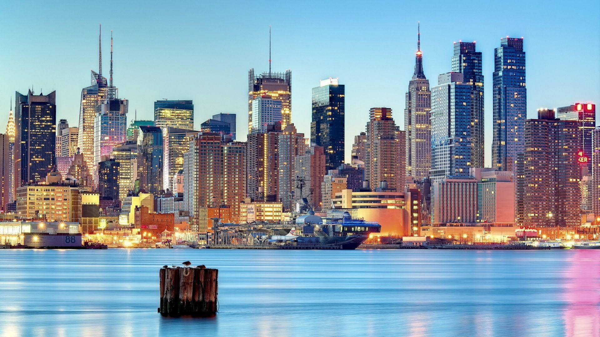 New Jersey 桌布 壁紙 — 紐約市天際線的壯麗暮色景觀，明亮的摩天大樓倒映在平靜的水面上。
