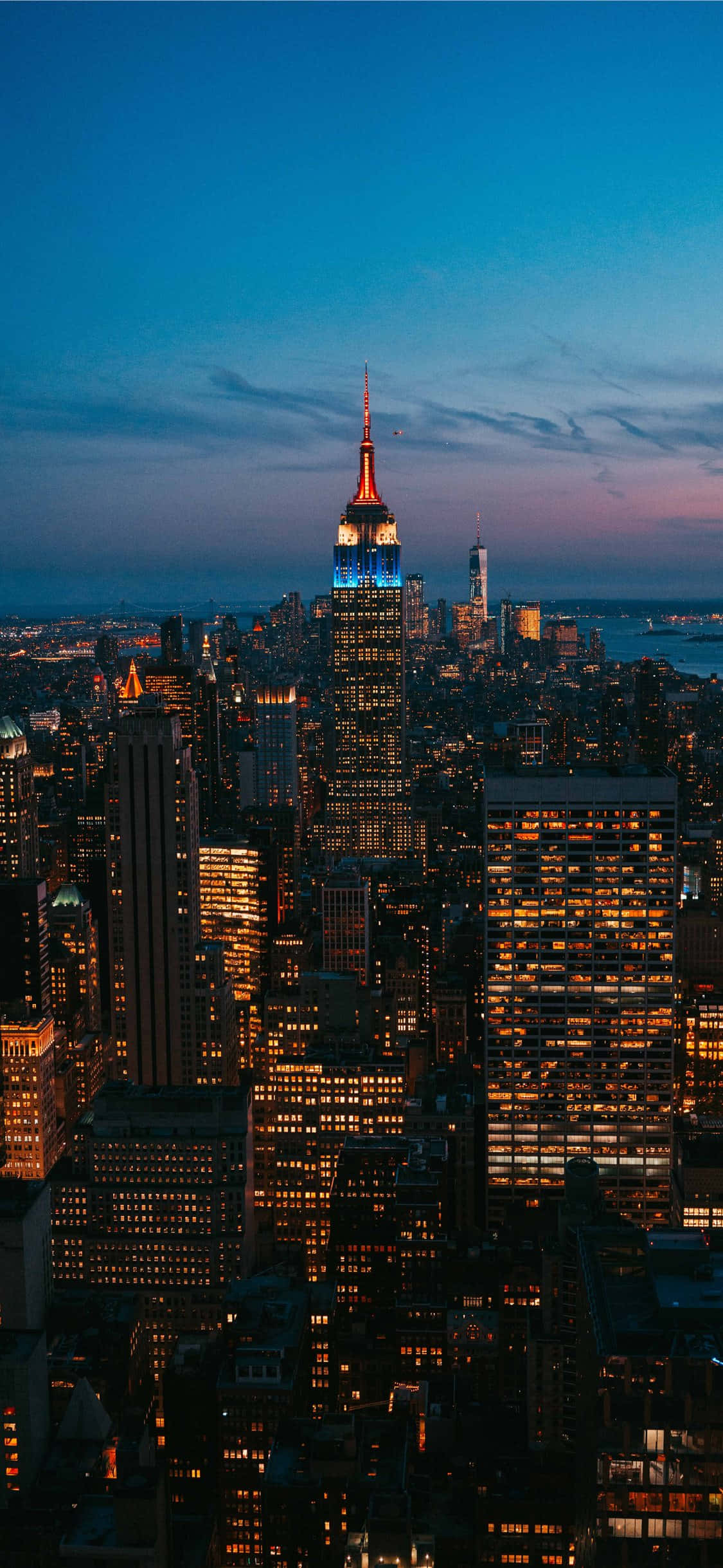 New York 桌布 壁紙 — 紐約市天際線的壯麗黃昏景色，帝國大廈在深藍色天空中閃耀。