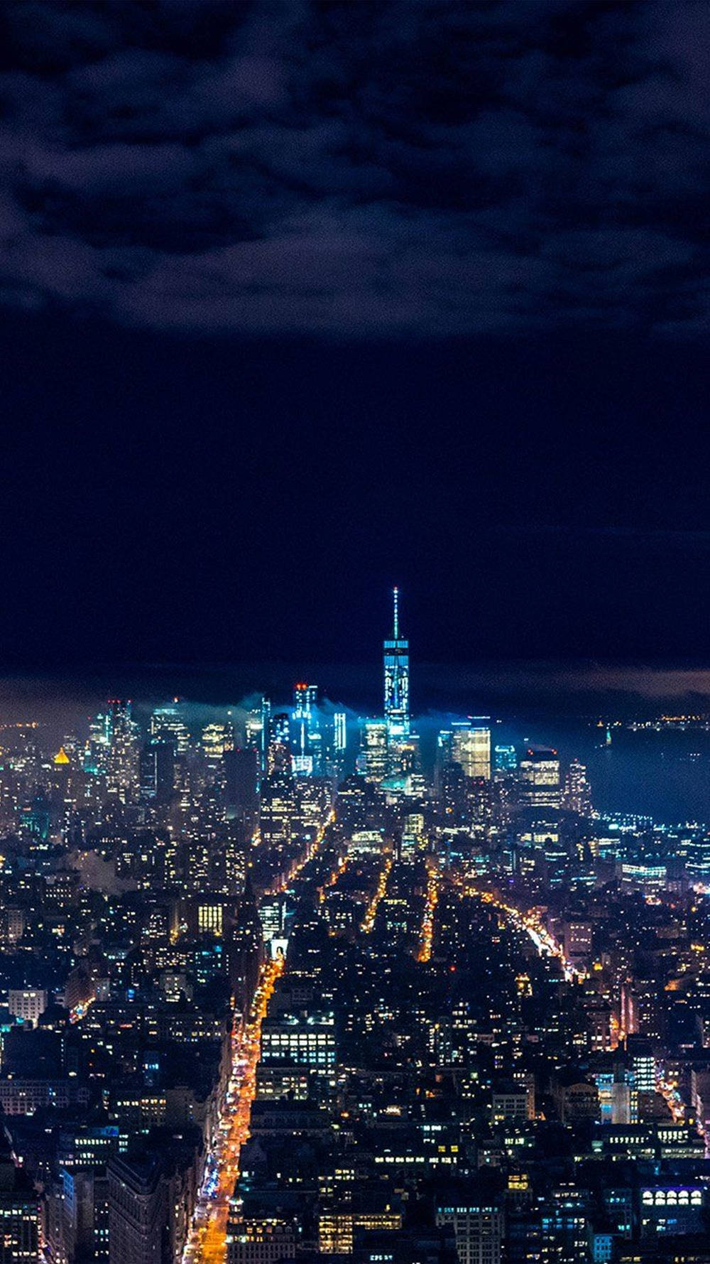 New 桌布 壁紙 — 紐約市天際線的夜間空中景觀，摩天大樓閃閃發光，街道照明，天空陰暗多雲。