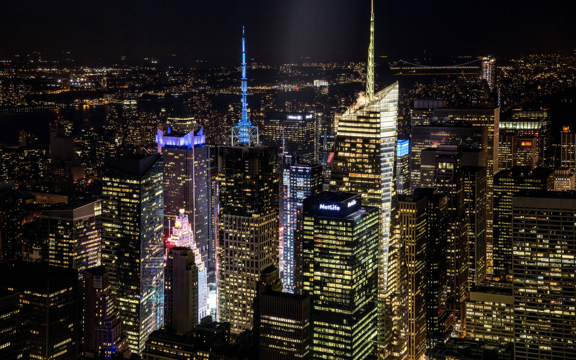 New York Skyline 桌布 壁紙 — 紐約市天際線的夜間空中景觀，摩天大樓燈火通明，窗戶在黑暗的天空下閃閃發光。