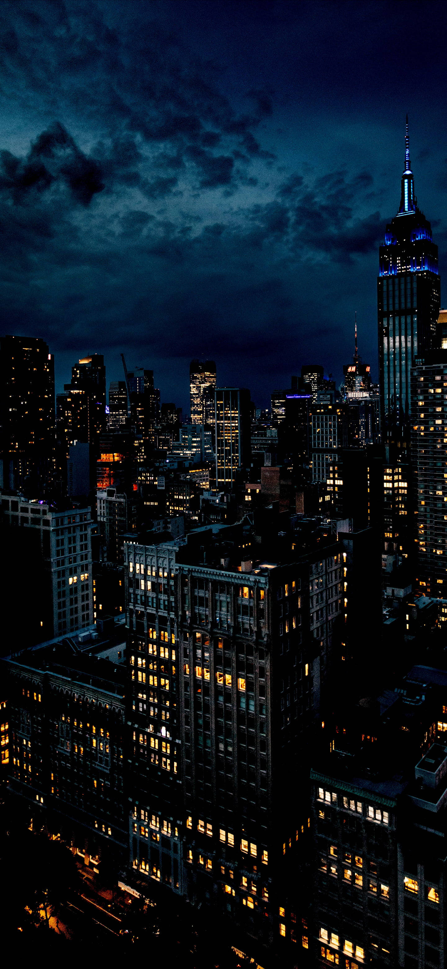 夜空 桌布 壁紙 — 紐約市天際線的戲劇性夜景，在深藍色多雲的天空下，摩天大樓燈火通明。