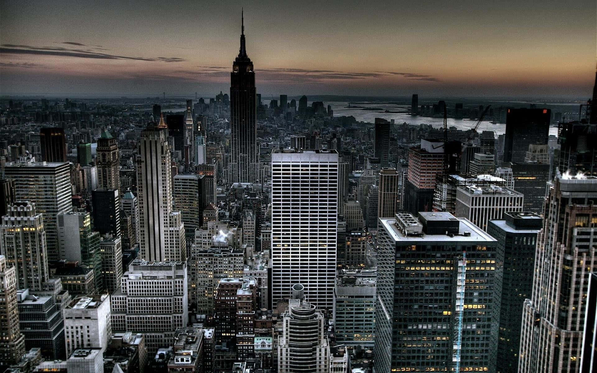 New York City At Night 桌布 壁紙 — 紐約市天際線的戲劇性暮色景觀，帝國大廈聳立在密集的摩天大樓和發光的窗戶之上。