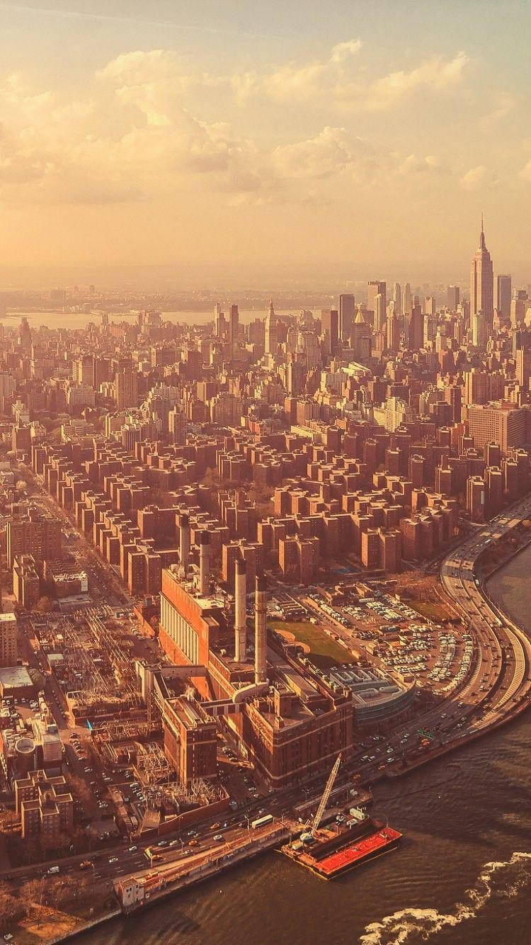 New York 桌布 壁紙 — 紐約市天際線的空中景觀，沐浴在金黃色的日落光芒中，下方有雲和河流。