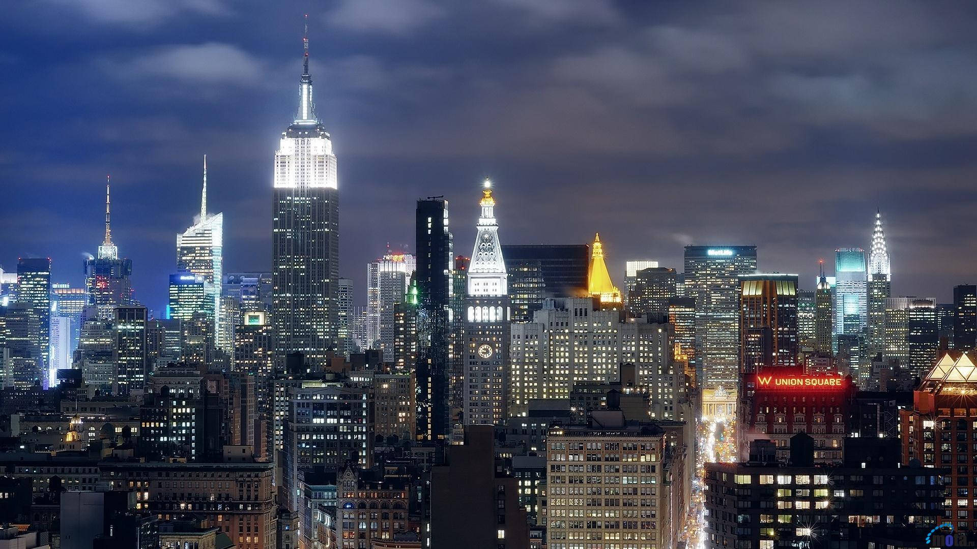 empire 桌布 壁紙 — 紐約市天際線的迷人夜景，燈火通明的摩天大樓刺穿陰鬱的藍色天空。