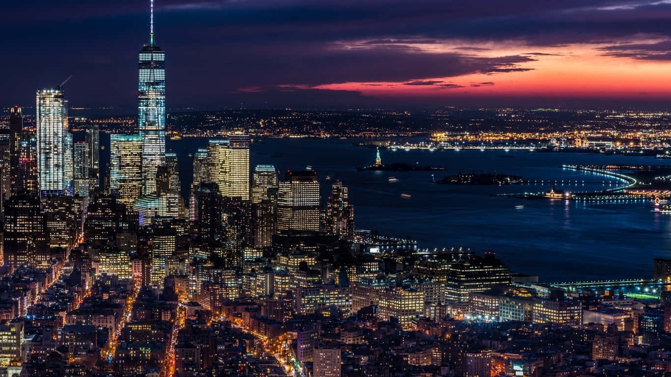 1366x768 Empire State Building 桌布 壁紙 — 紐約市天際線的迷人黃昏景色，閃爍的摩天大樓和水面上充滿活力的橙色和紫色天空。
