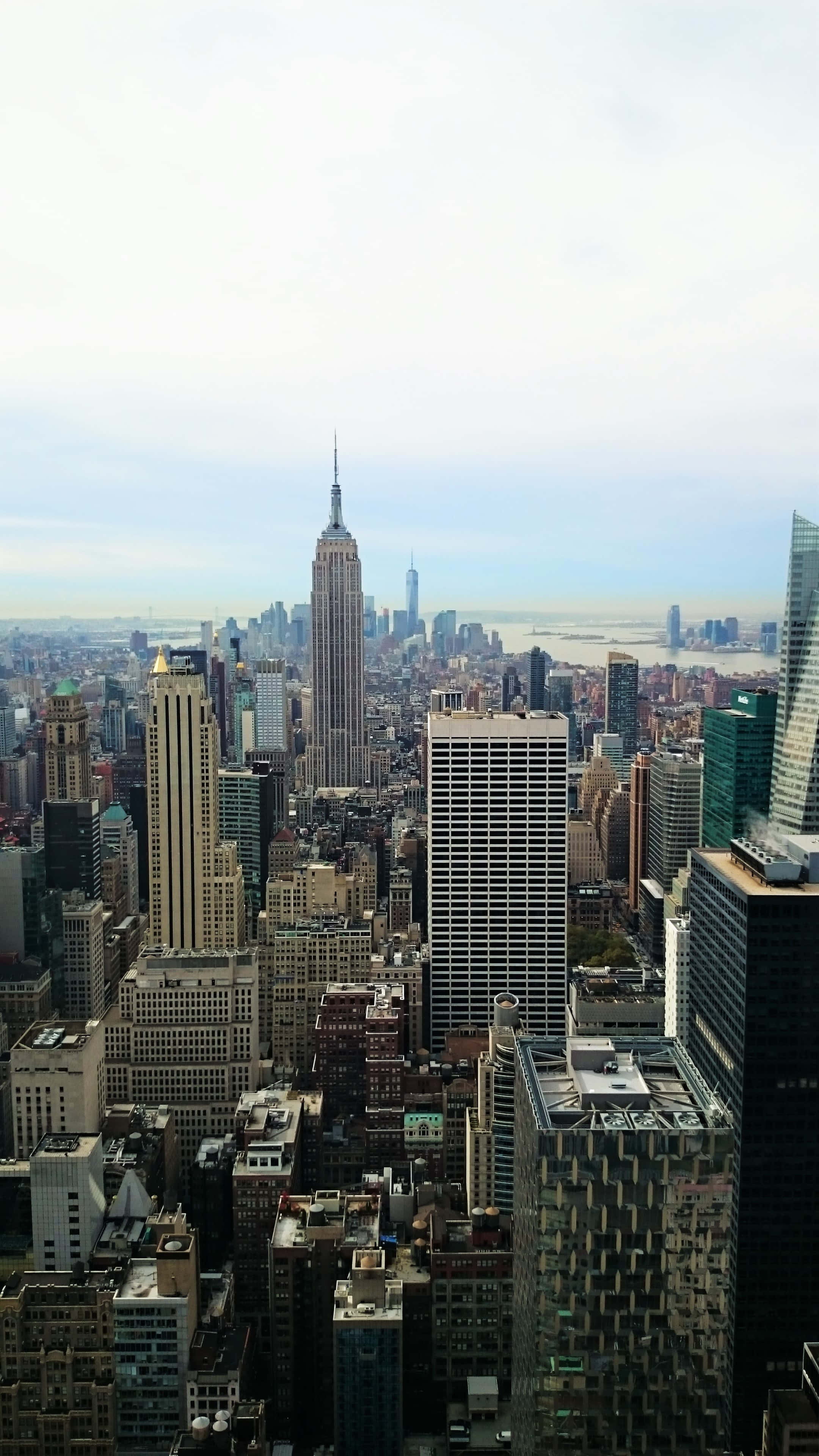 New York State 桌布 壁紙 — 紐約市天際線的鳥瞰圖，帝國大廈在朦朧的天空下佔據主導地位。