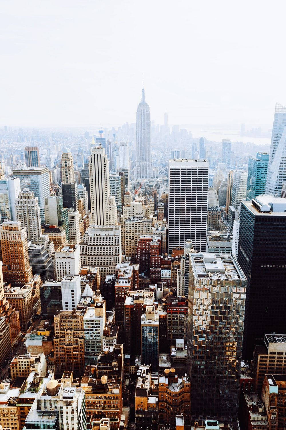 New York 桌布 壁紙 — 紐約市天際線的鳥瞰圖，帝國大廈在朦朧的日光下聳立於密集的城市建築之上。