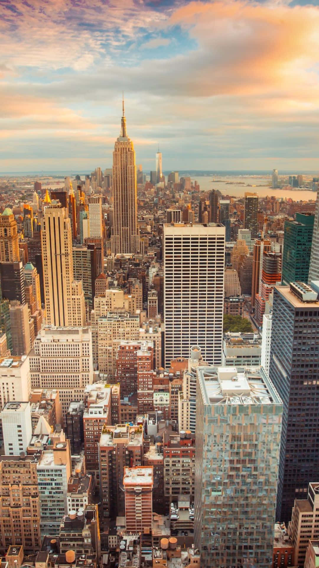 Android Ny City 桌布 壁紙 — 紐約市天際線的鳥瞰圖，日落時分，金色光芒照亮摩天大樓和雲層。