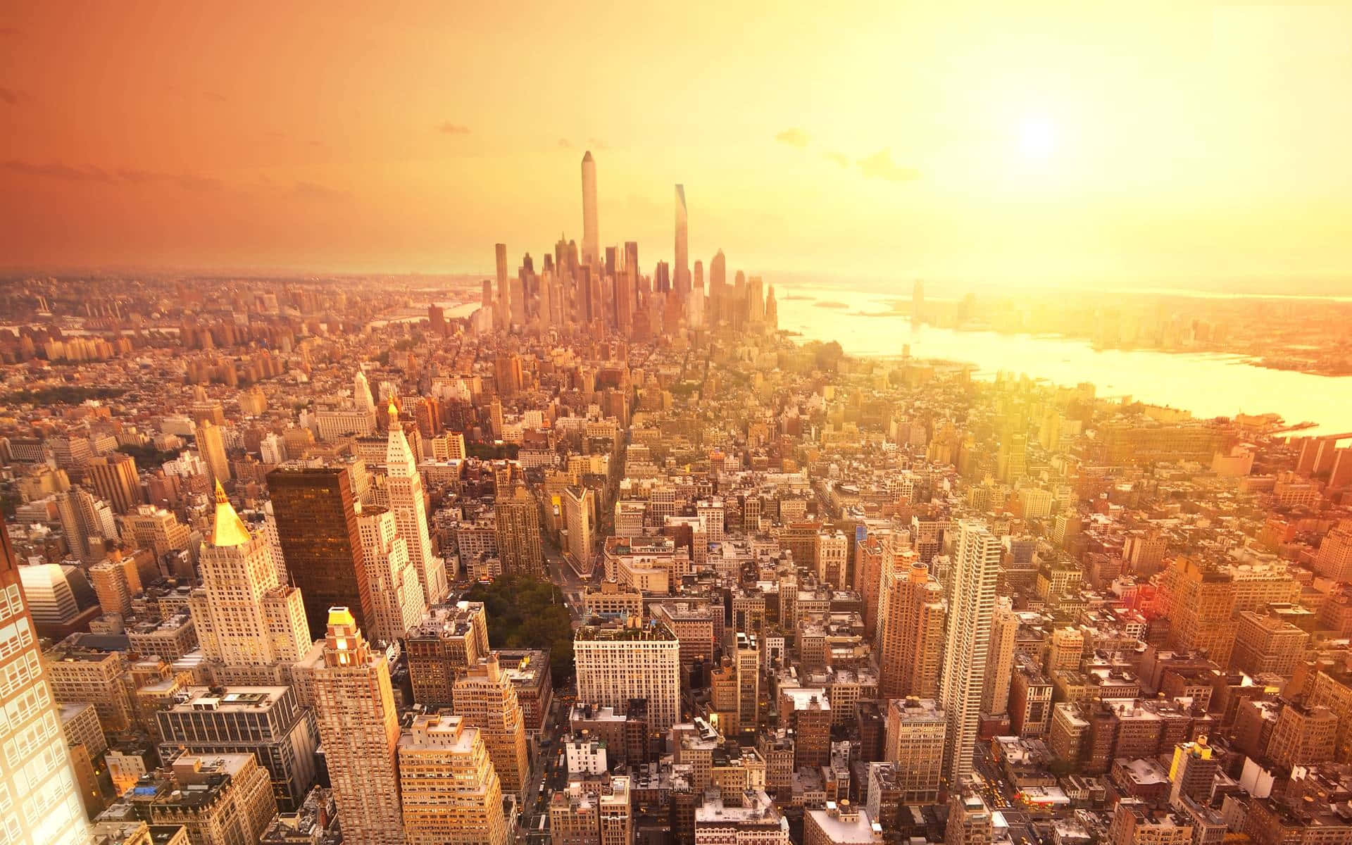 Nyc 桌布 壁紙 — 紐約市天際線的鳥瞰圖，沐浴在金黃色的日落光芒中，摩天大樓和河流溫暖地發光。