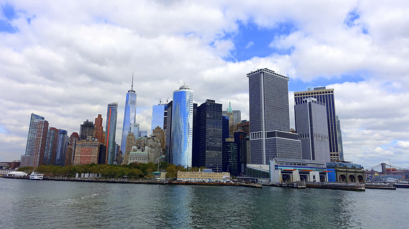 1366x768 Empire State Building 桌布 壁紙 — 紐約市標誌性天際線的全景，摩天大樓在平靜的水面上倒映出藍天和白雲。