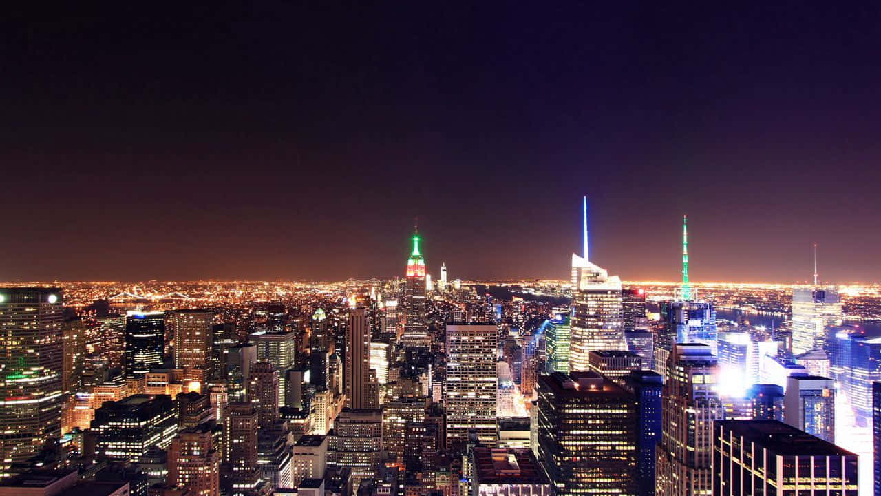720p Ny City 桌布 壁紙 — 紐約市璀璨夜景全景，標誌性摩天大樓在深紫色天空下閃耀。