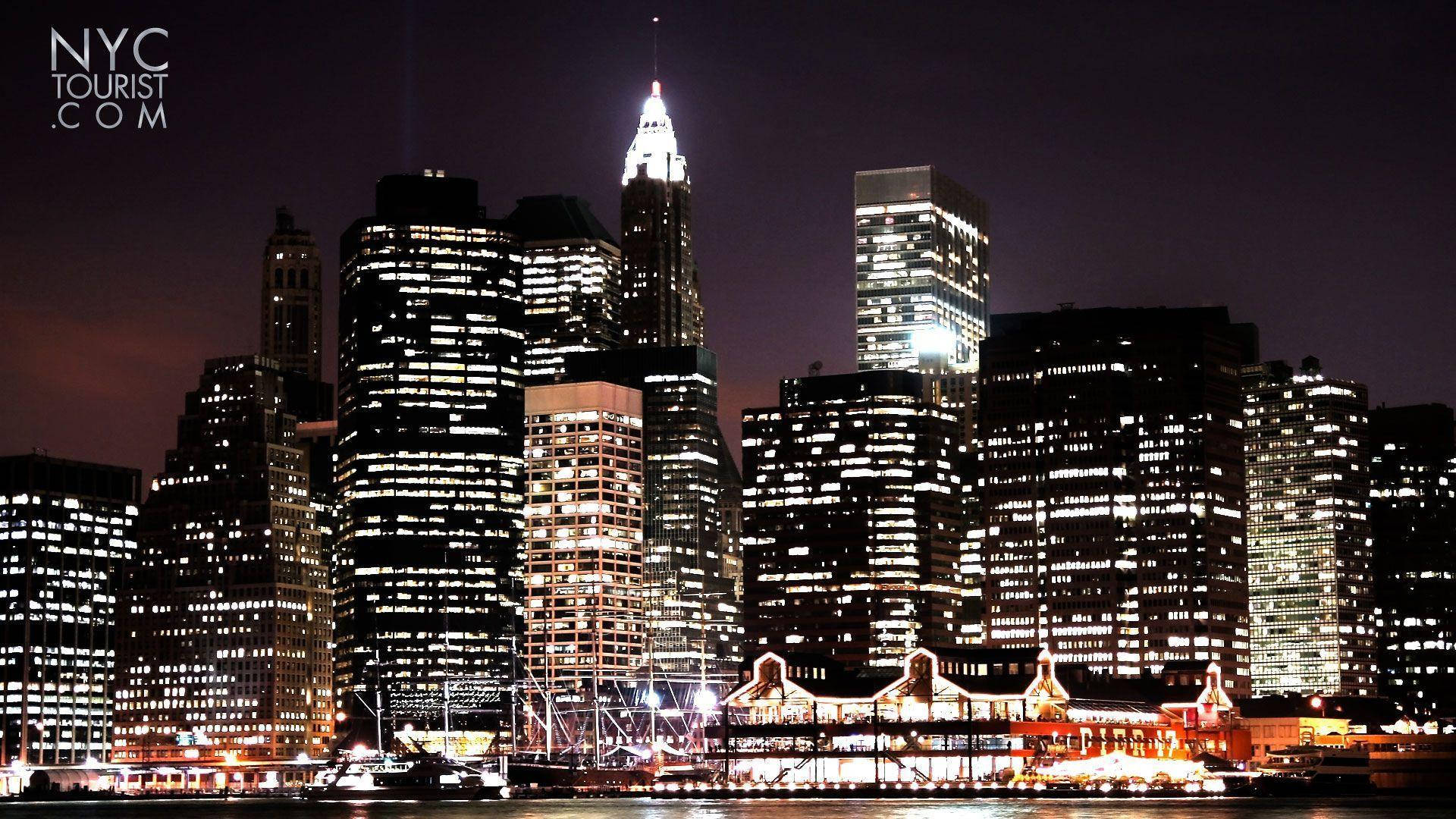 New York 桌布 壁紙 — 紐約市璀璨的夜景，摩天大樓的燈光倒映在水面上，前景是燈火通明的碼頭。