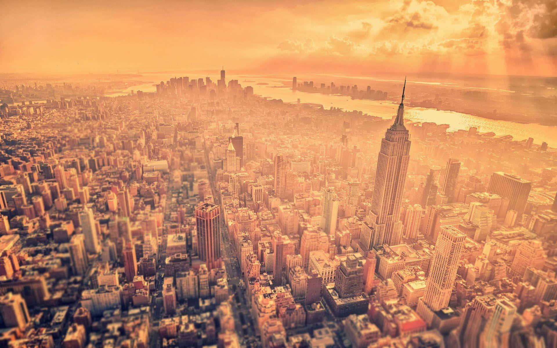 Nyc Skyline 桌布 壁紙 — 紐約市的鳥瞰圖，沐浴在金色的日落光芒中，帝國大廈聳立在密集的城市擴張之上。