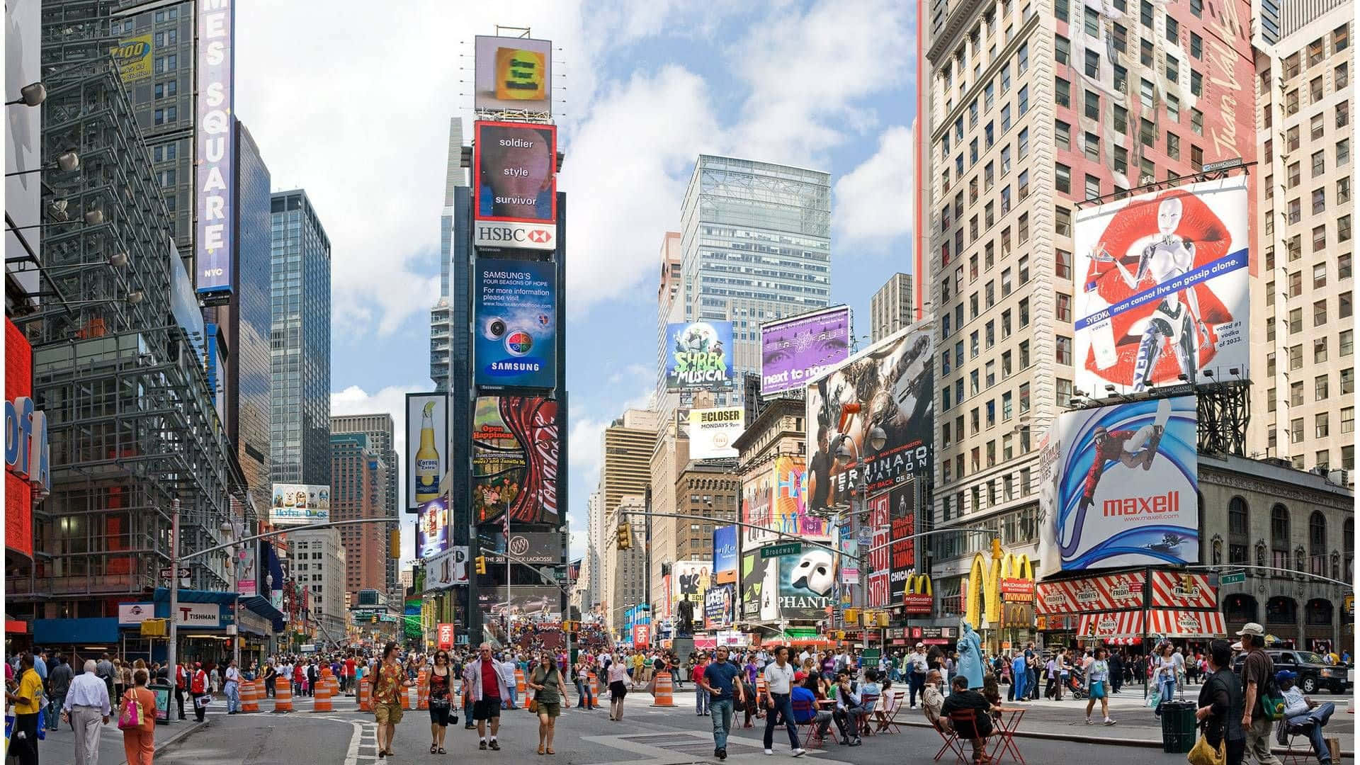 New York 桌布 壁紙 — 紐約市繁華的時代廣場，擠滿人群、行人、高聳的摩天大樓和耀眼的數位廣告看板，在明亮的藍天下。