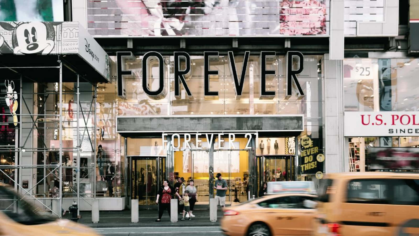 永遠21 桌布 壁紙 — 紐約市繁華的街景，有Forever 21商店、行人及移動模糊的黃色計程車。