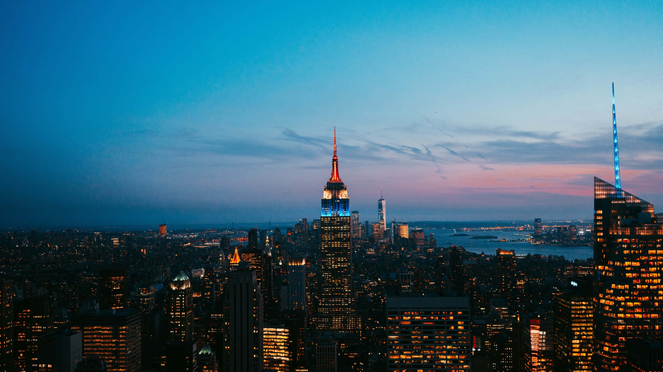 1440p Empire State Building 桌布 壁紙 — 紐約市黃昏時分天際線，帝國大廈在暮色中閃耀。