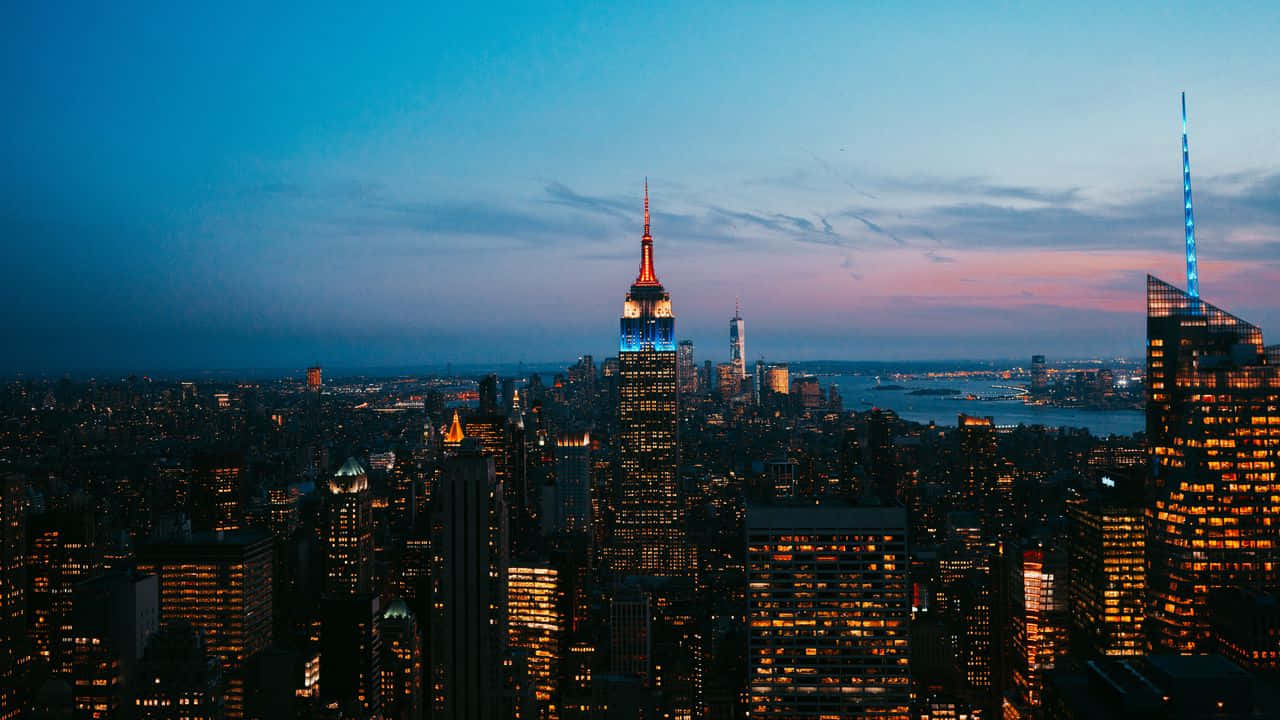 720p Ny City 桌布 壁紙 — 紐約市黃昏時分的全景，藍粉漸變天空下燈火通明的摩天大樓。