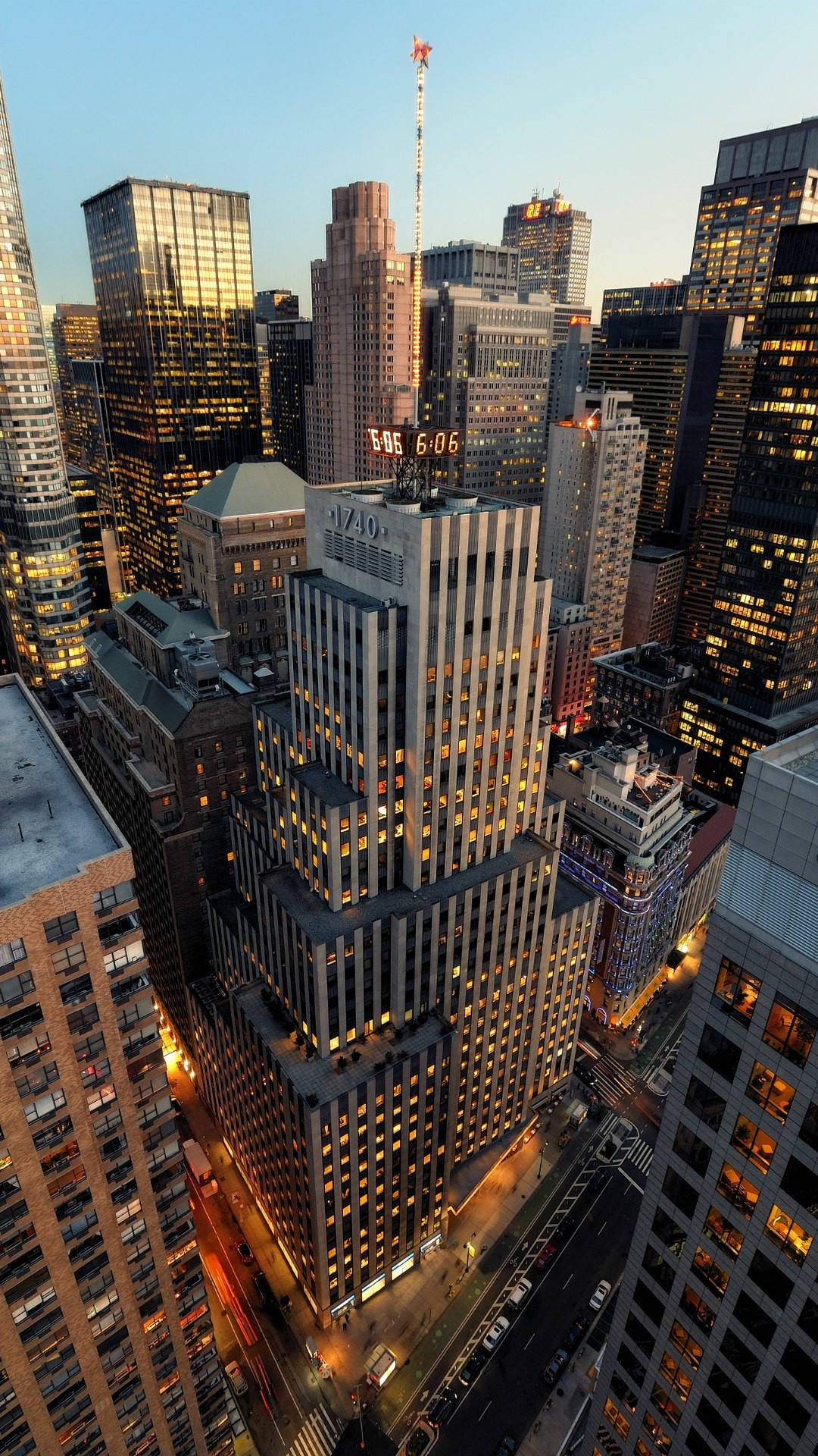 new york city iPhone x 桌布 壁紙 — 紐約市黃昏時分高聳摩天大樓的鳥瞰圖，窗戶和下方街道閃爍著金色燈光。