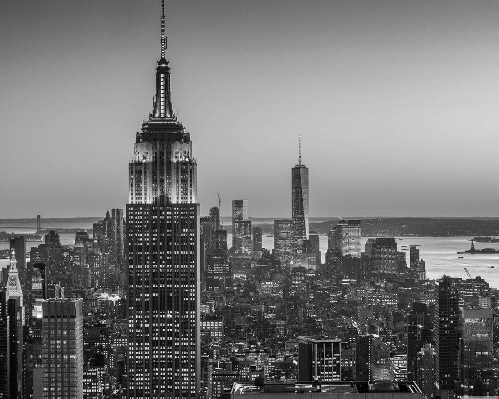 New York 桌布 壁紙 — 紐約市黃昏時的單色天際線，帝國大廈和世界貿易中心一號樓在漸暗的天空中亮起。