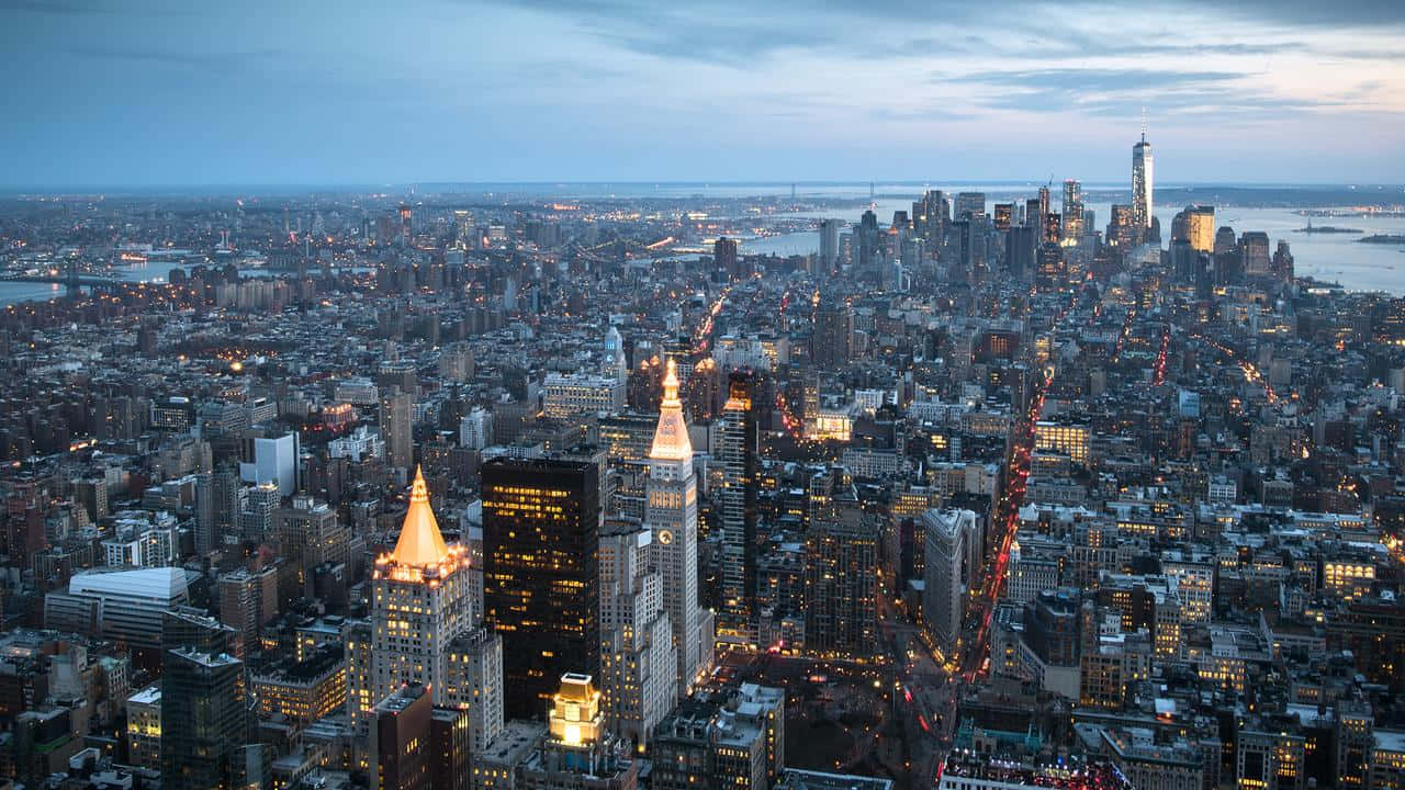 720p Empire State Building 桌布 壁紙 — 紐約市黃昏時的鳥瞰圖，摩天大樓燈火通明，街道在暮色中閃爍光芒。
