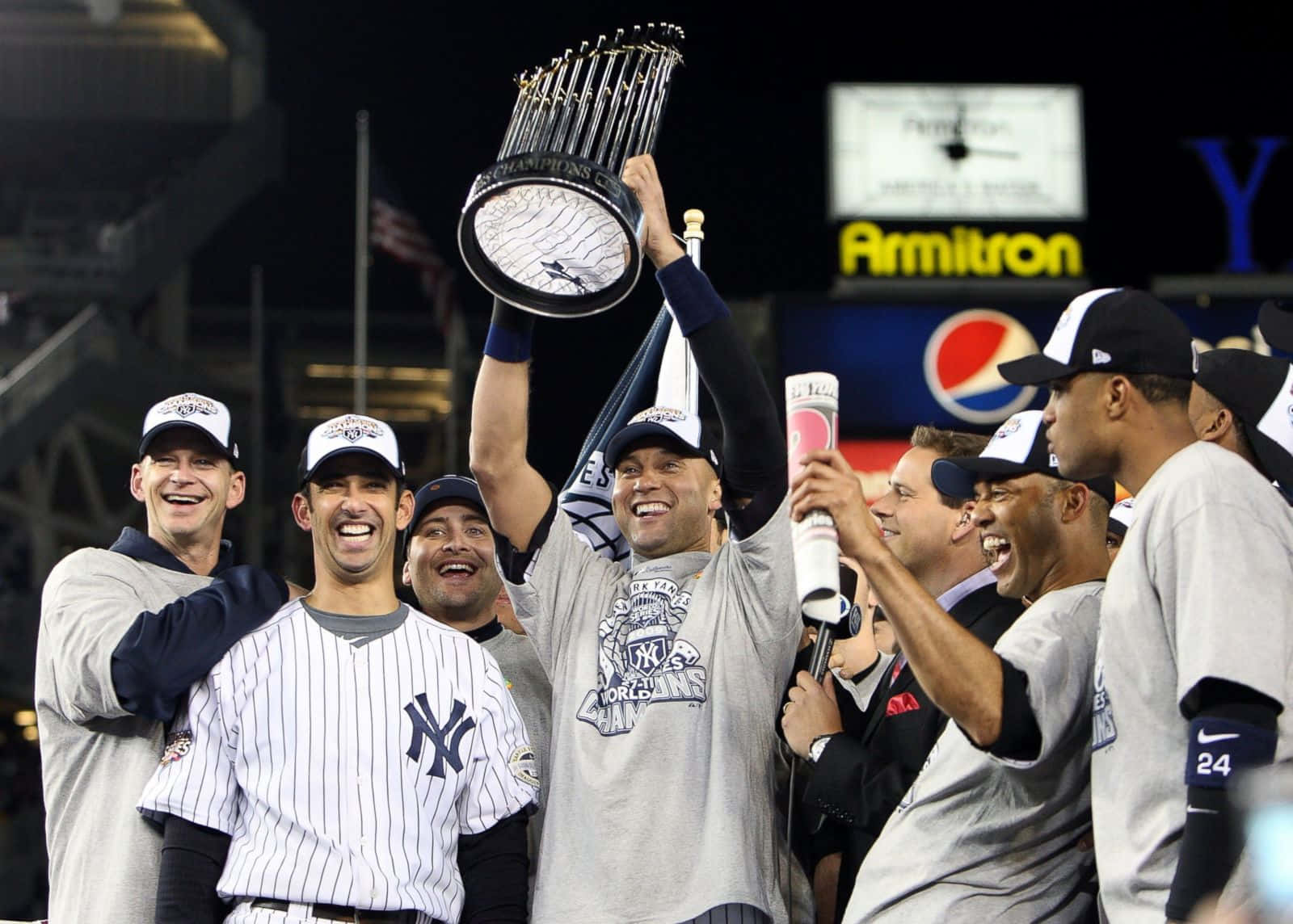 Derek Jeter 桌布 壁紙 — 紐約洋基隊球員在夜間勝利慶祝，在球場燈光下高舉世界大賽獎盃，面露喜悅。