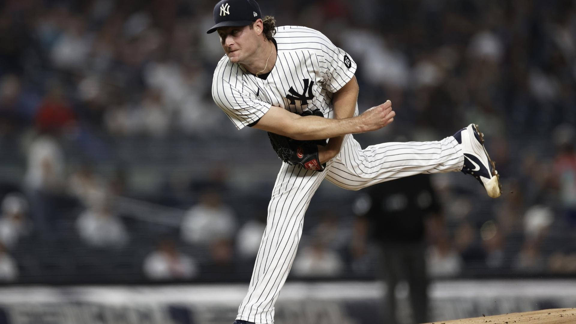 Gerrit Cole 桌布 壁紙 — 紐約洋基隊的投手穿著細條紋球衣，在夜間棒球比賽中於球場燈光下投出強力一球。