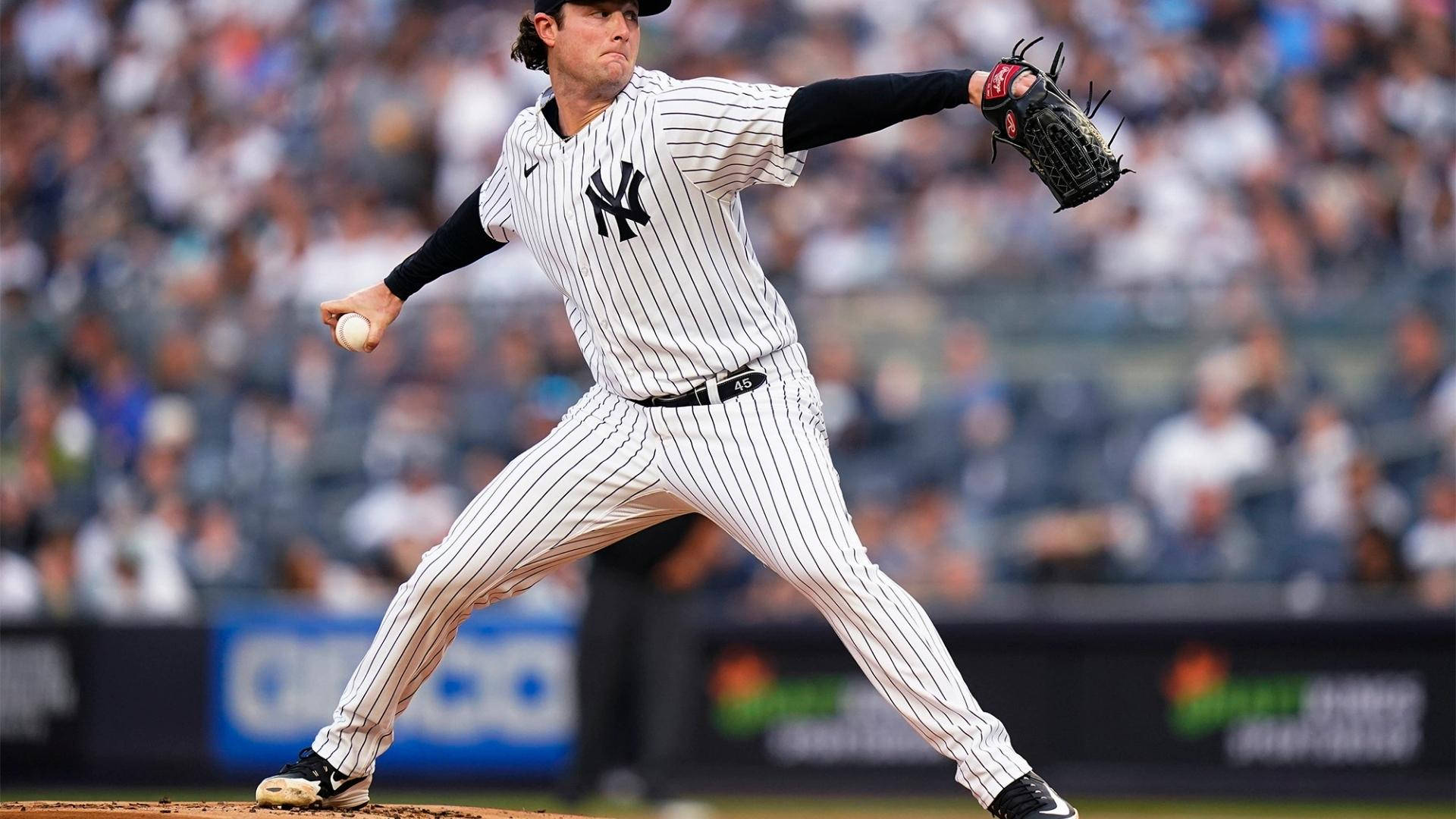 Gerrit Cole 桌布 壁紙 — 紐約洋基隊的投手身穿細條紋球衣，在日間棒球比賽中做出強力投球，背景是模糊的人群。