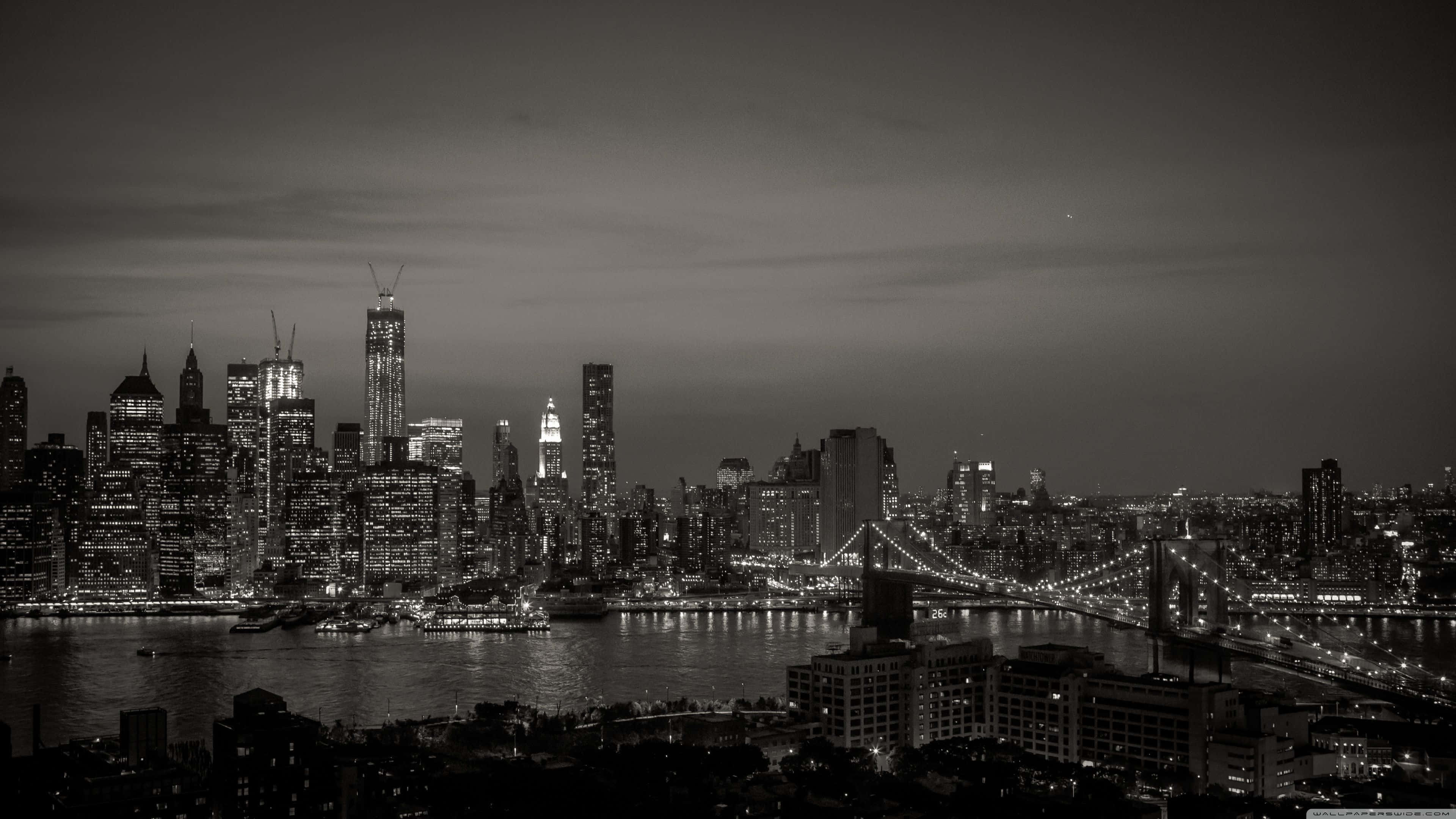 桌布 壁紙 — 紐約的單色夜景，黑暗的河流上橫跨著布魯克林大橋，摩天大樓燈火通明。