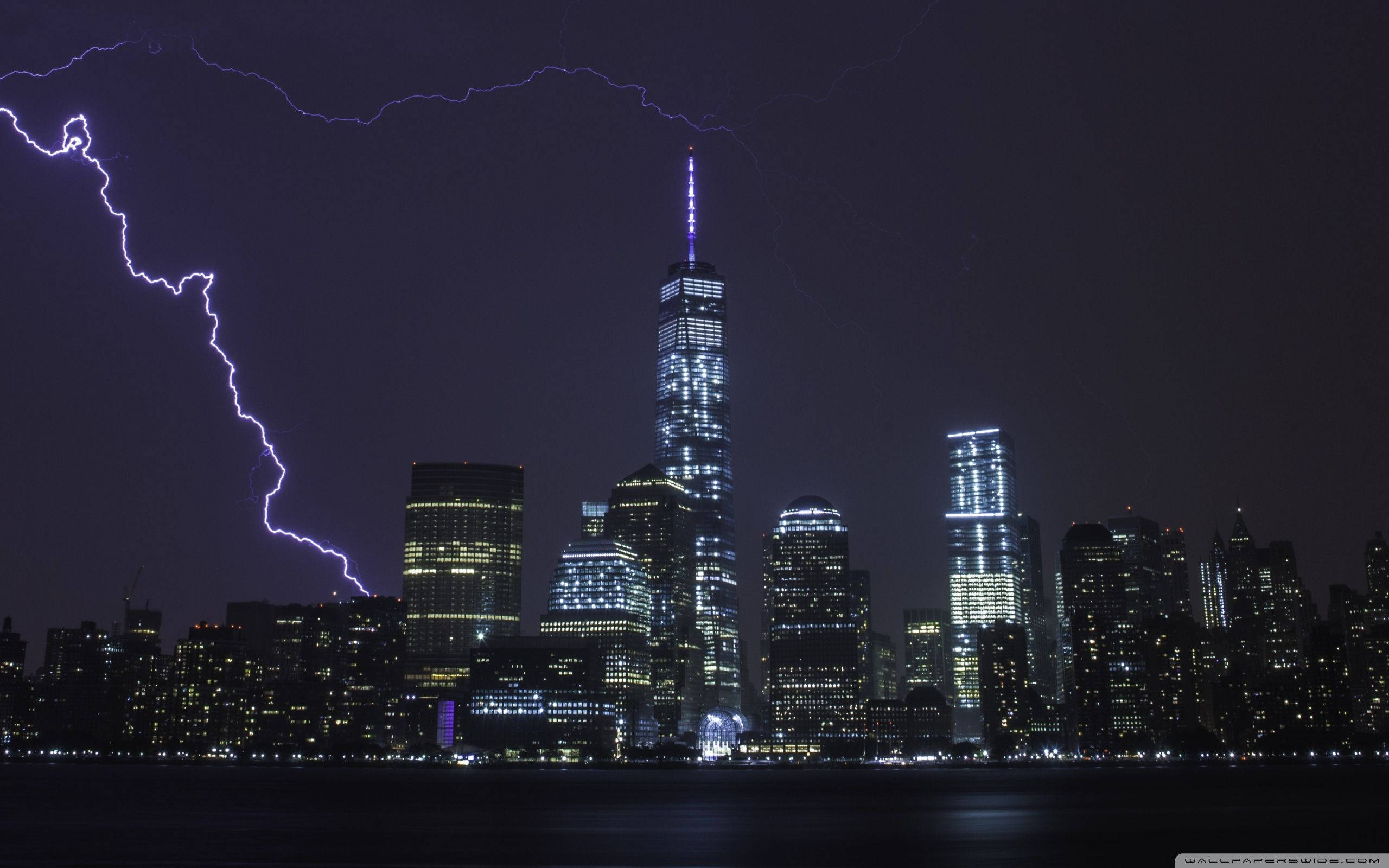 閃電 桌布 壁紙 — 紐約的戲劇性夜景，一道鮮豔的紫色閃電擊中在燈火通明的摩天大樓之上。