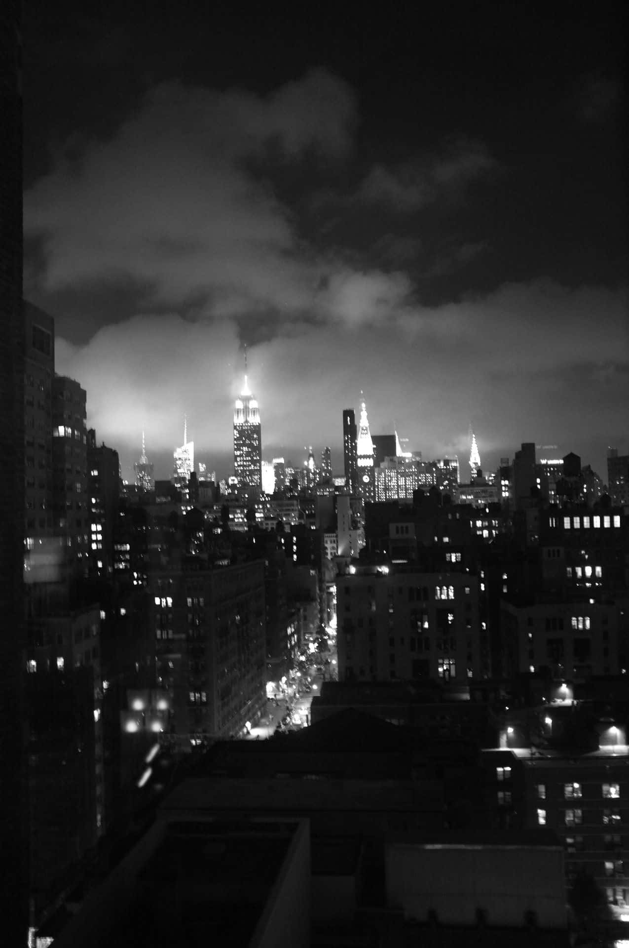 黑白美學動圖 桌布 壁紙 — 紐約的黑白夜景城市景觀，明亮的摩天大樓穿過多雲的天空。