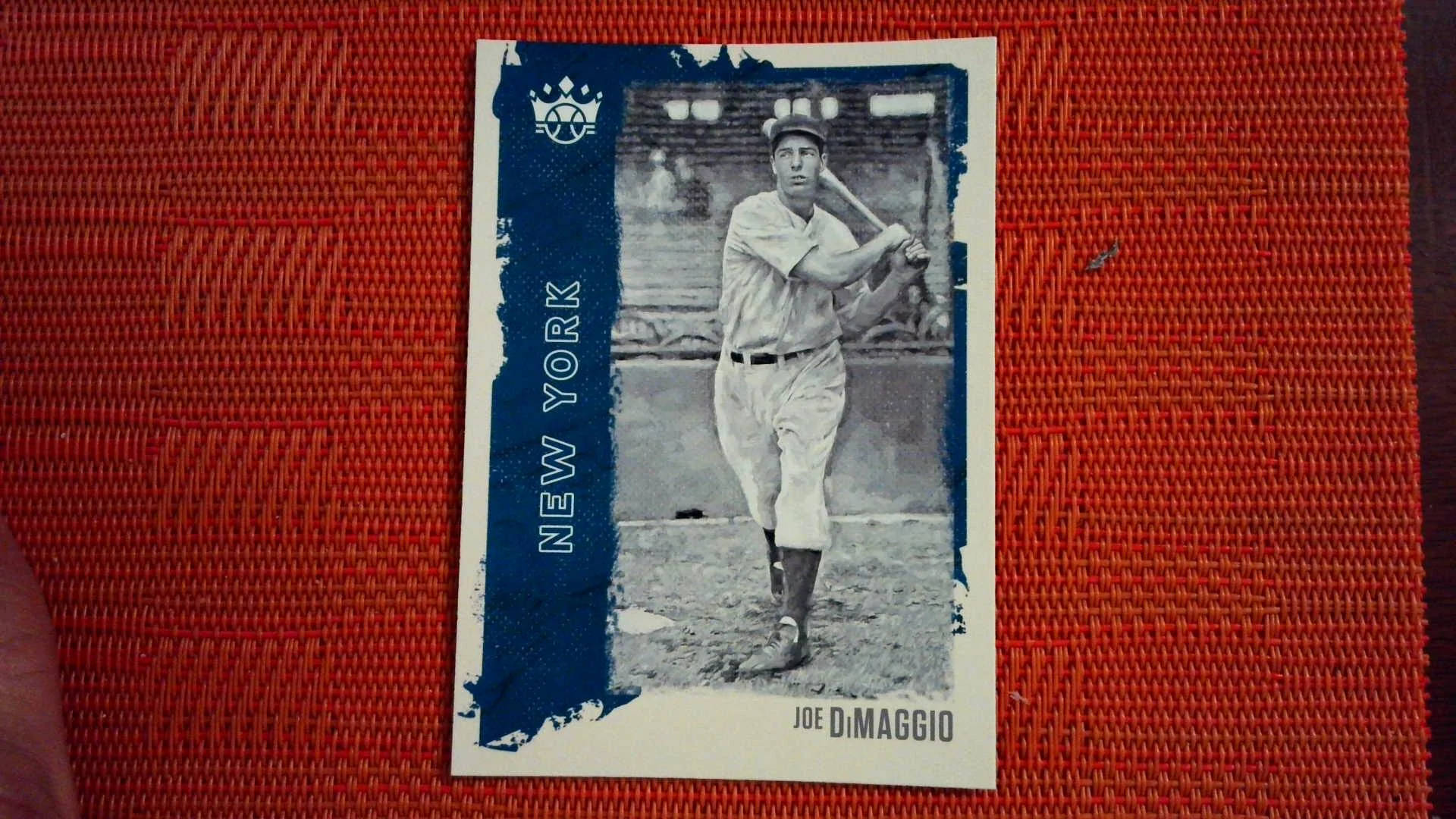 Joe Dimaggio 桌布 壁紙 — 紐約隊球衣的喬·迪馬吉奧復古棒球卡，在紋理紅色編織背景中擺出揮棒中途的姿勢。