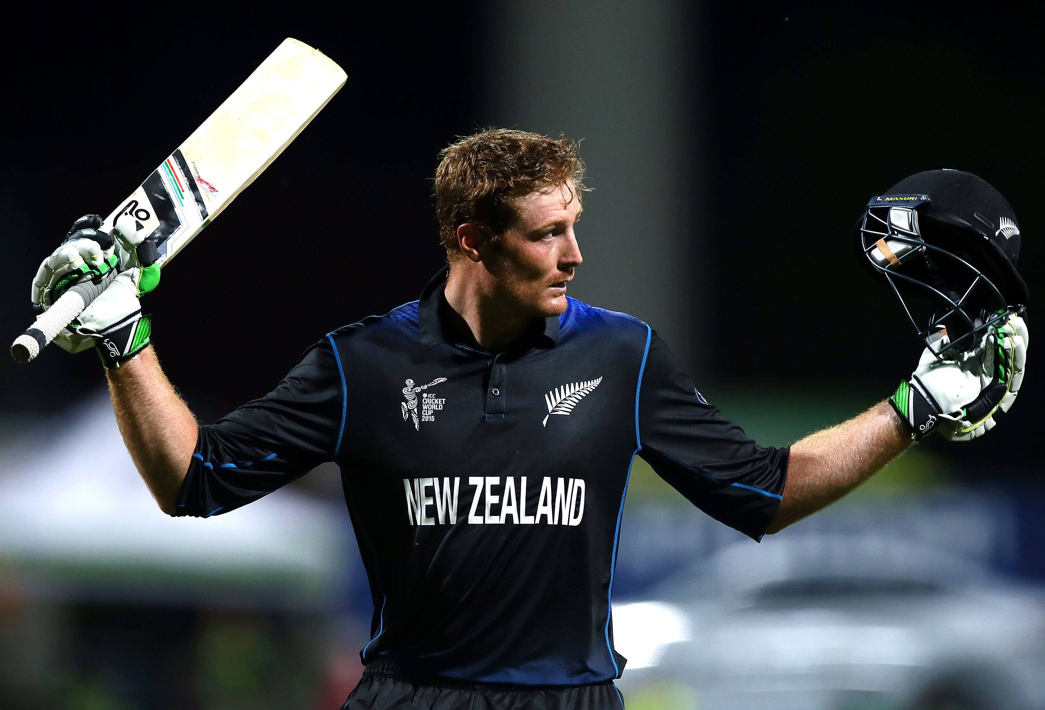 martin guptill 桌布 壁紙 — 紐西蘭板球運動員在比賽後於體育場燈光下勝利地舉起球棒和頭盔。