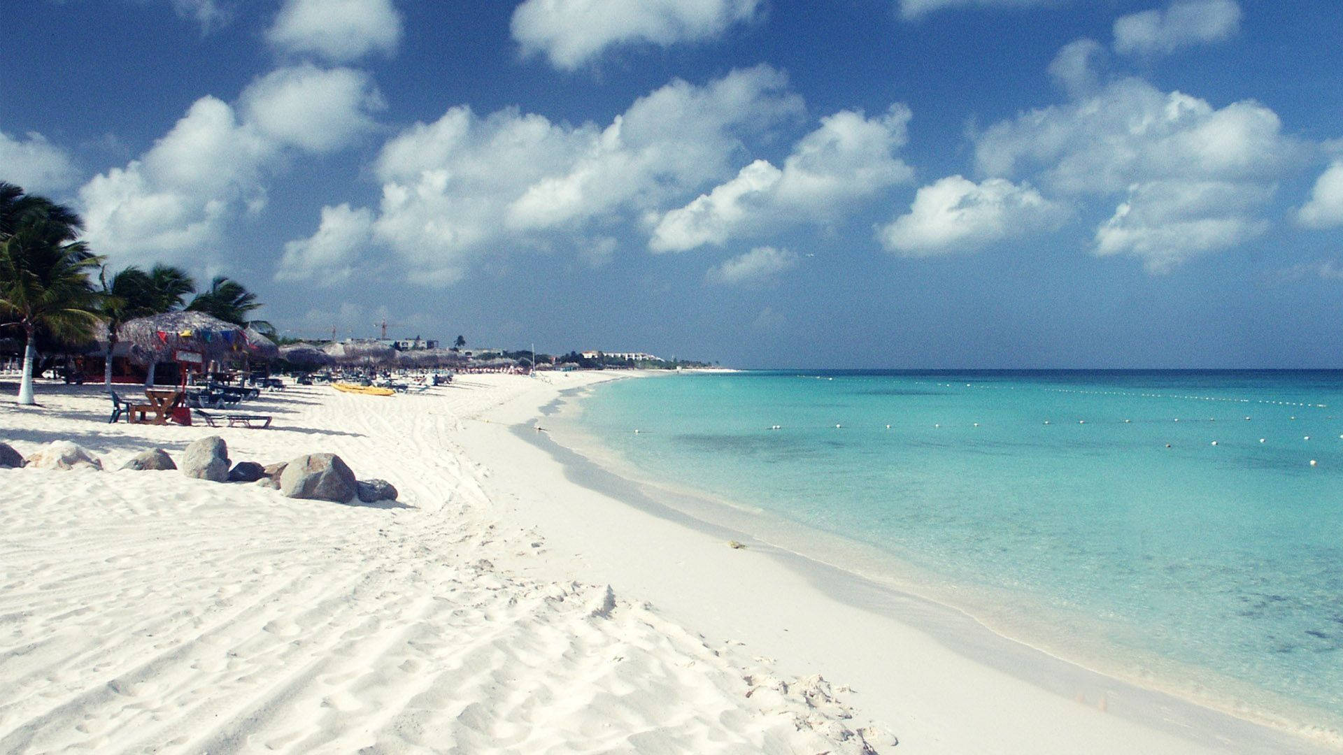 Aruba 桌布 壁紙 — 純白沙灘沿著碧綠海水蜿蜒，上方是藍天白雲。