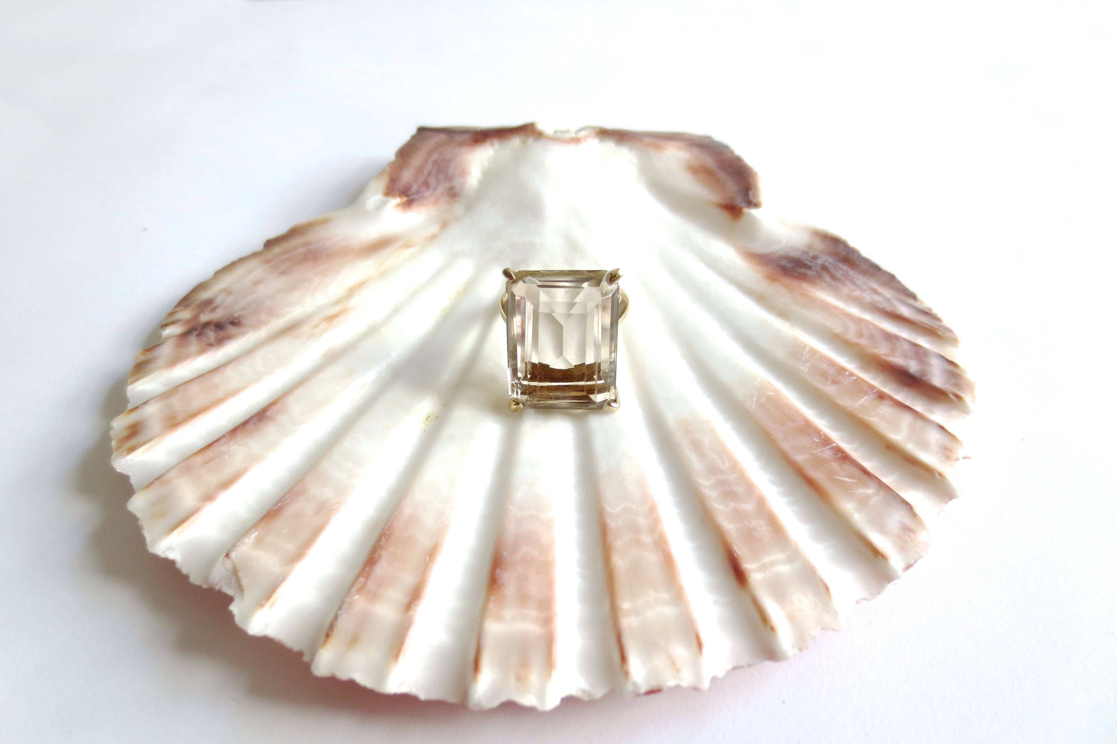 Seashell 桌布 壁紙 — 純白背景上，一隻潔淨的扇貝托著一枚方形切割鑽石戒指。